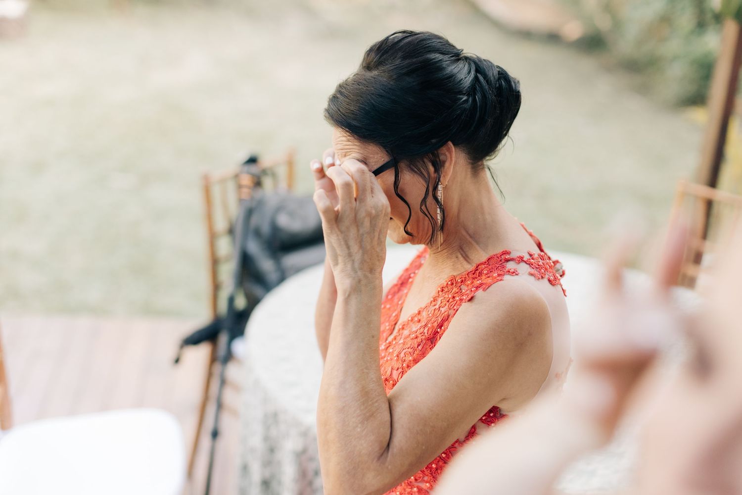 Emotional moment captured during wedding preparations with guest in coral dress.