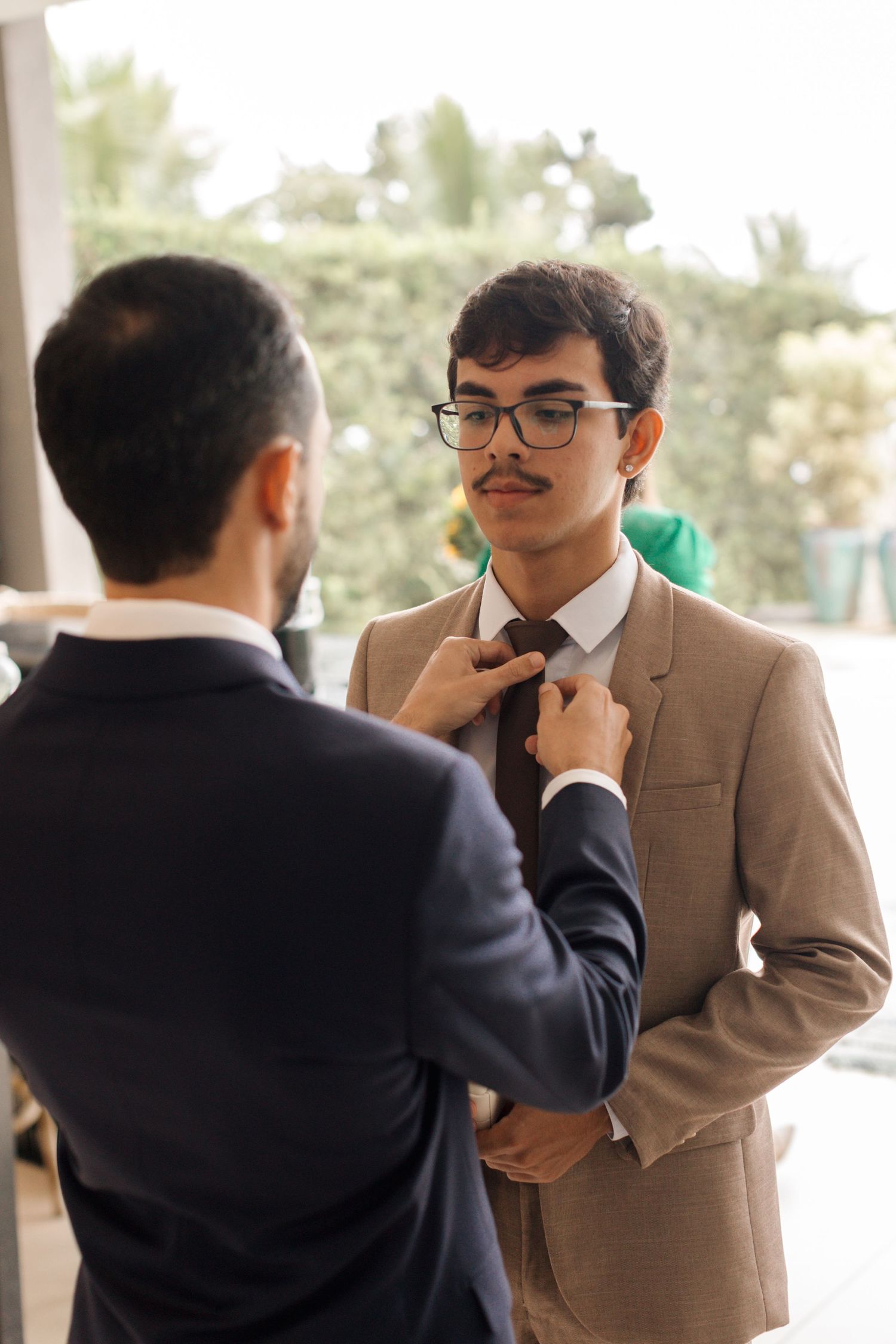 Two people help adjust formal attire before an event.