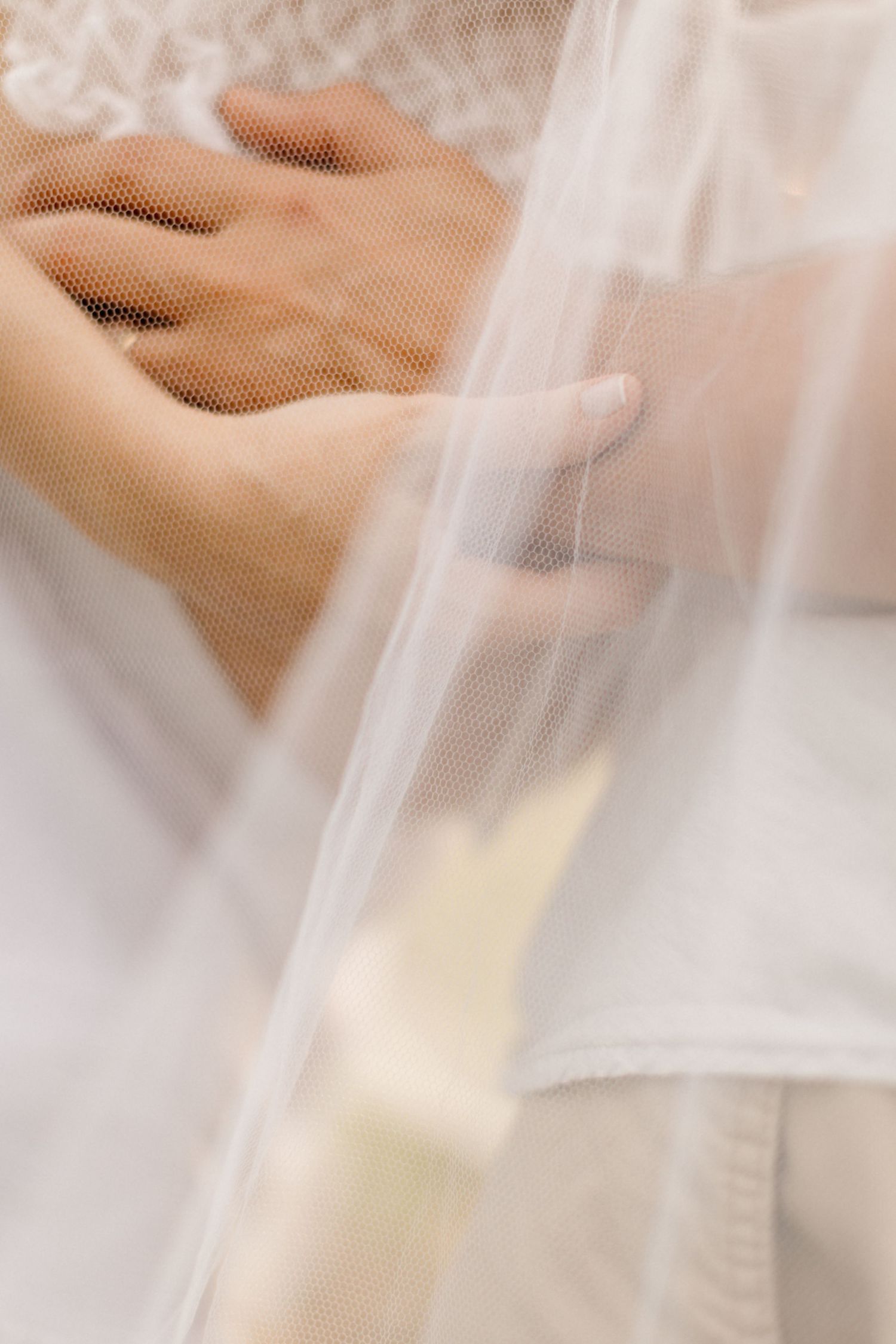 Soft and ethereal close-up of delicate white lace fabric with gentle folds and dreamy lighting.