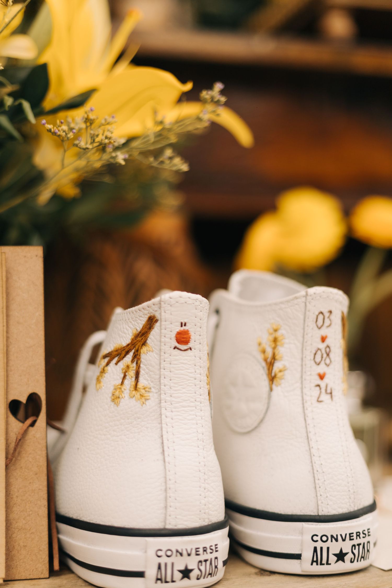 Close-up of customized white Converse All-Star sneakers decorated for a wedding.