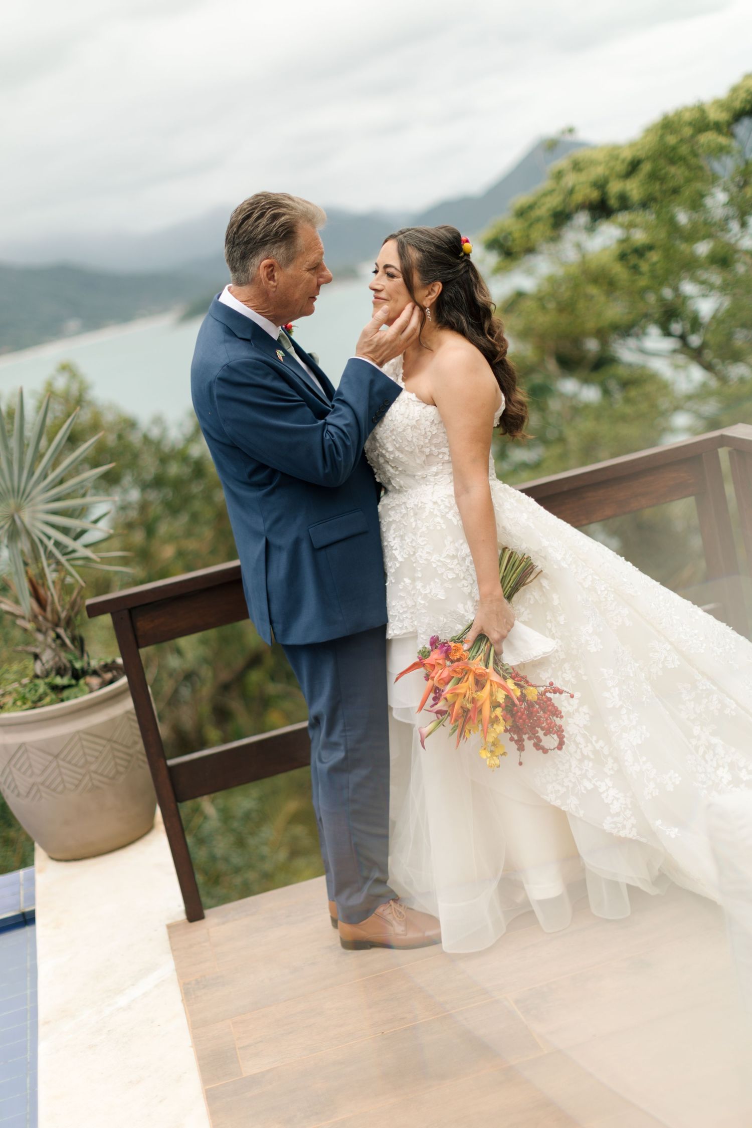 A romantic wedding couple shares an intimate moment on an outdoor terrace overlooking scenic mountain views.