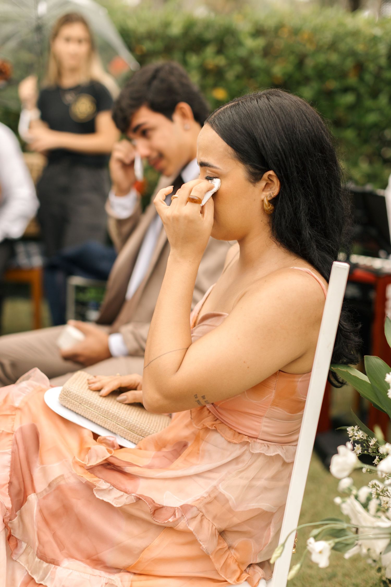 Wedding guests in formal attire show emotion during a touching ceremony moment.