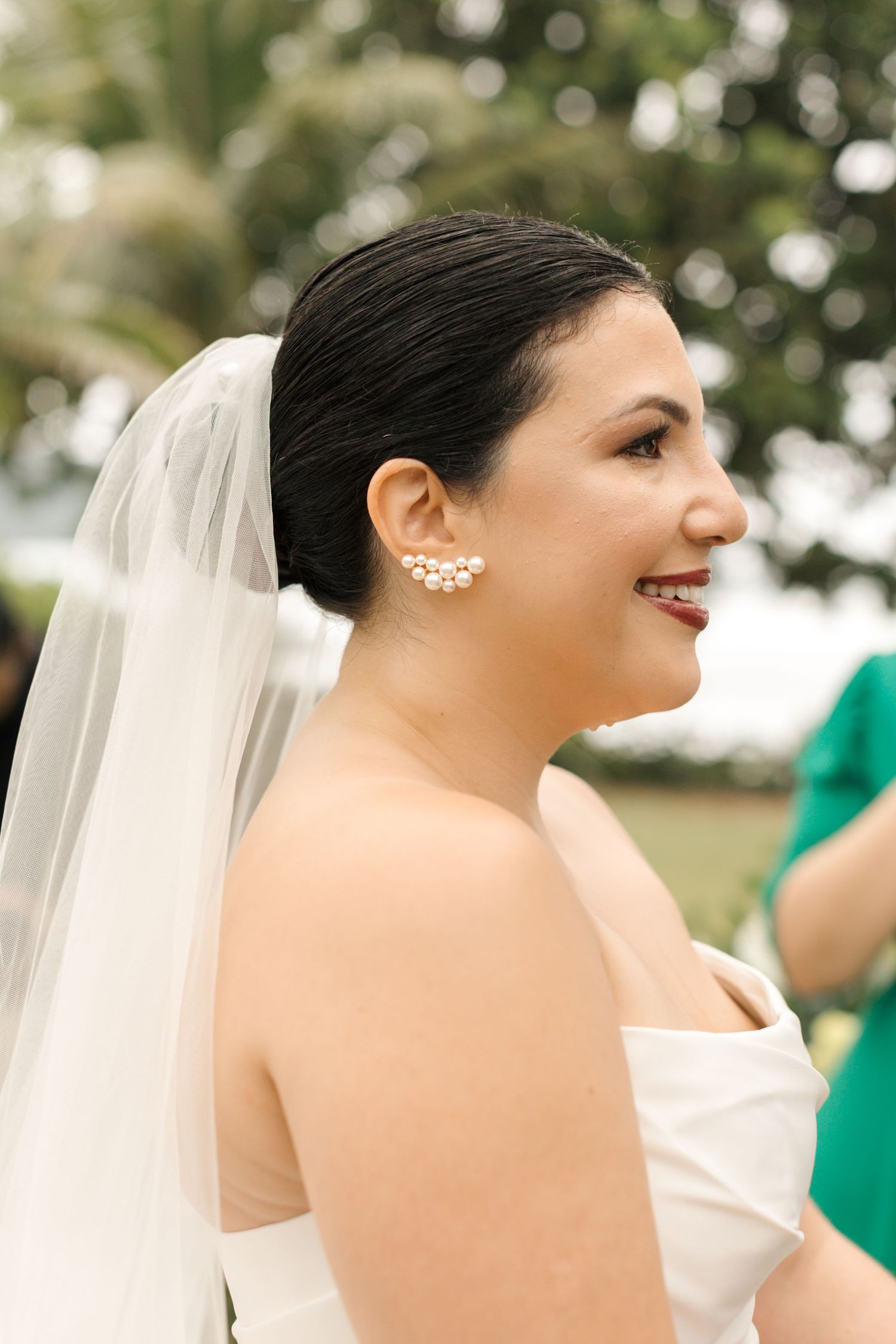 Elegant bride wearing pearl ear cuff and strapless white dress with veil.