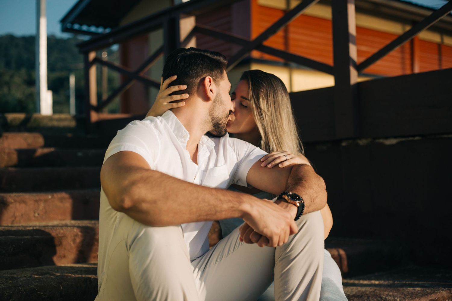 Intimate portrait of couple embracing on urban steps during sunset.