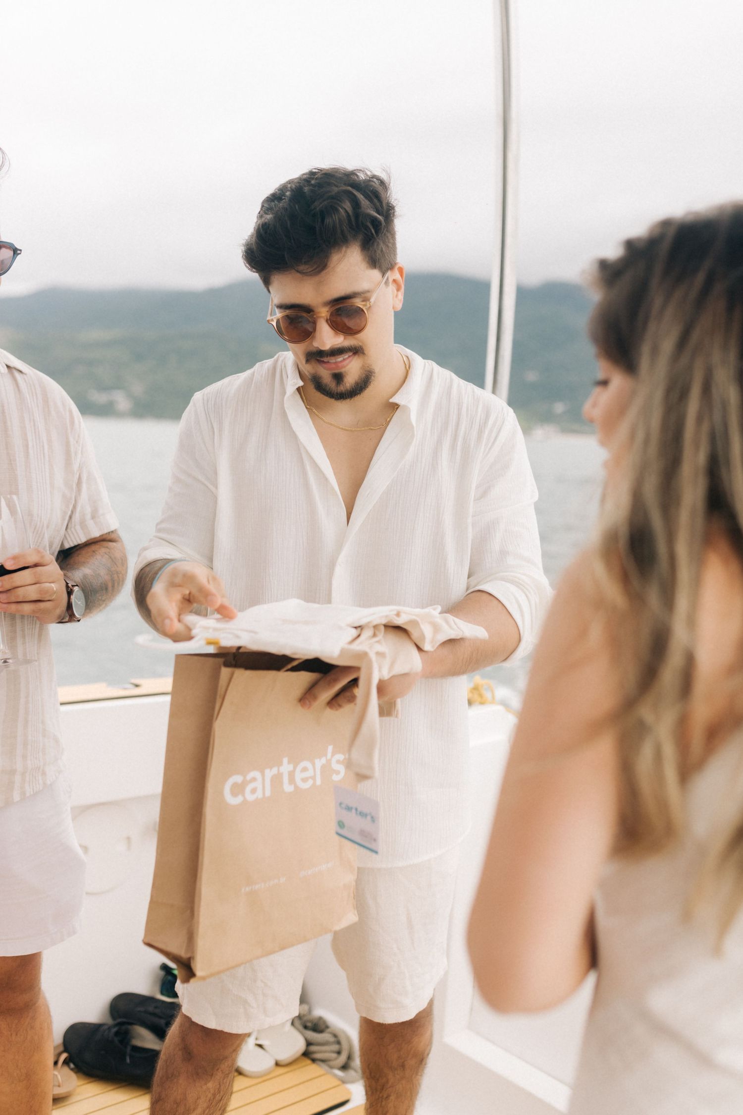 Person opening Carter's shopping bag during boat celebration with friends.