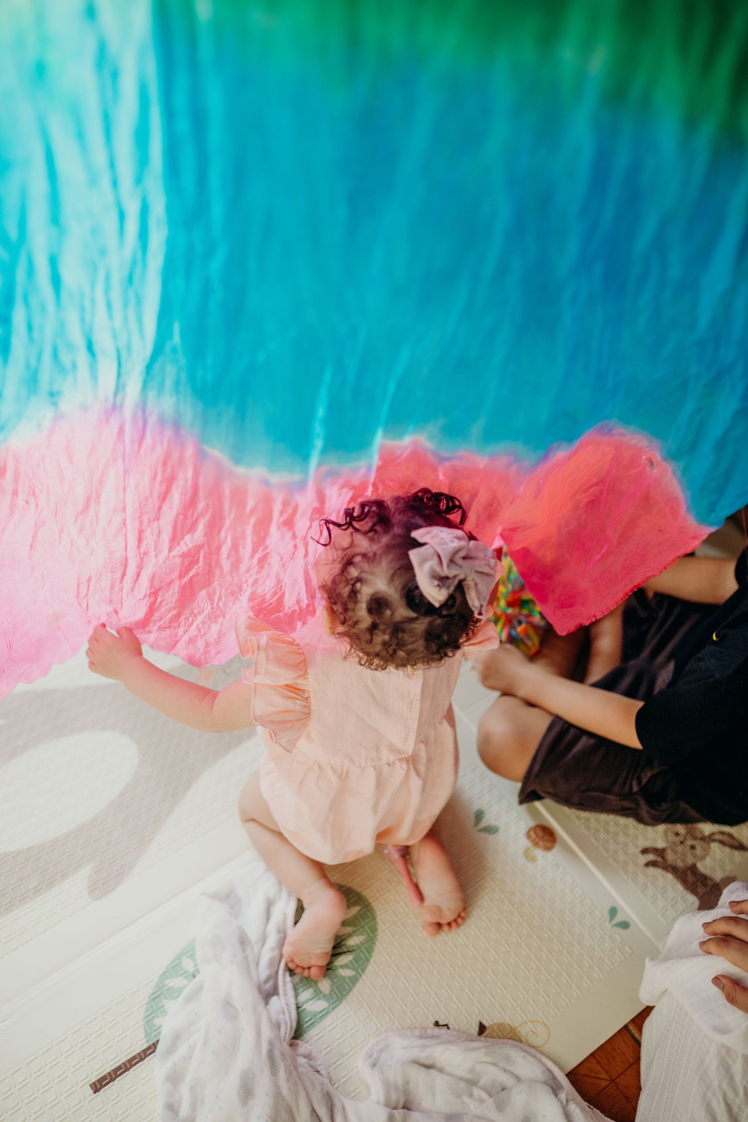 Pink and turquoise fabric creates a dreamy canopy effect over a play space.