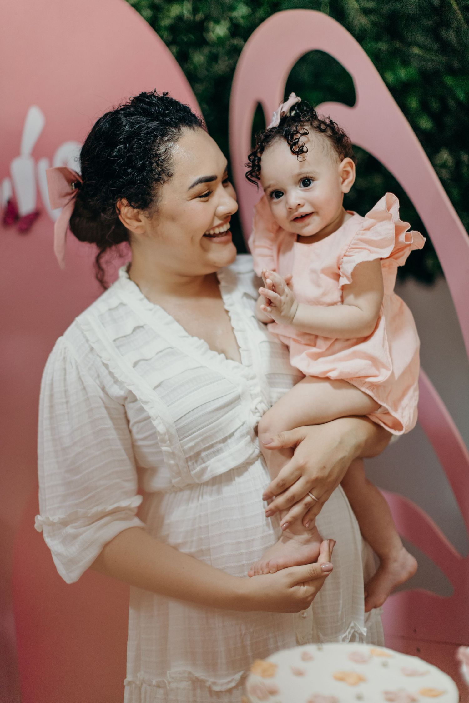 Candid moments of joy shared between adult and baby against a pink background.