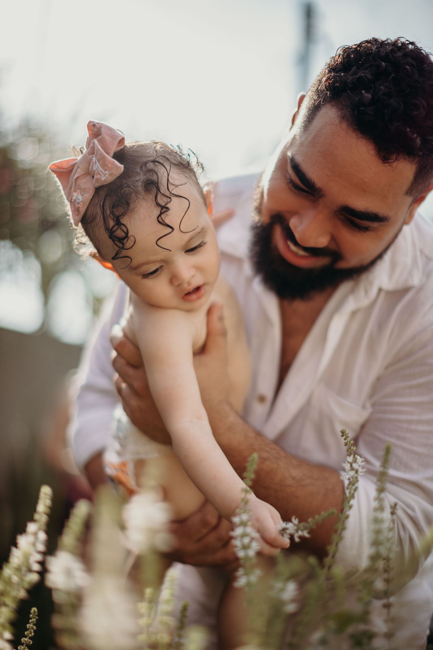 Tender moments shared between parent and baby in an outdoor garden setting with soft natural lighting.