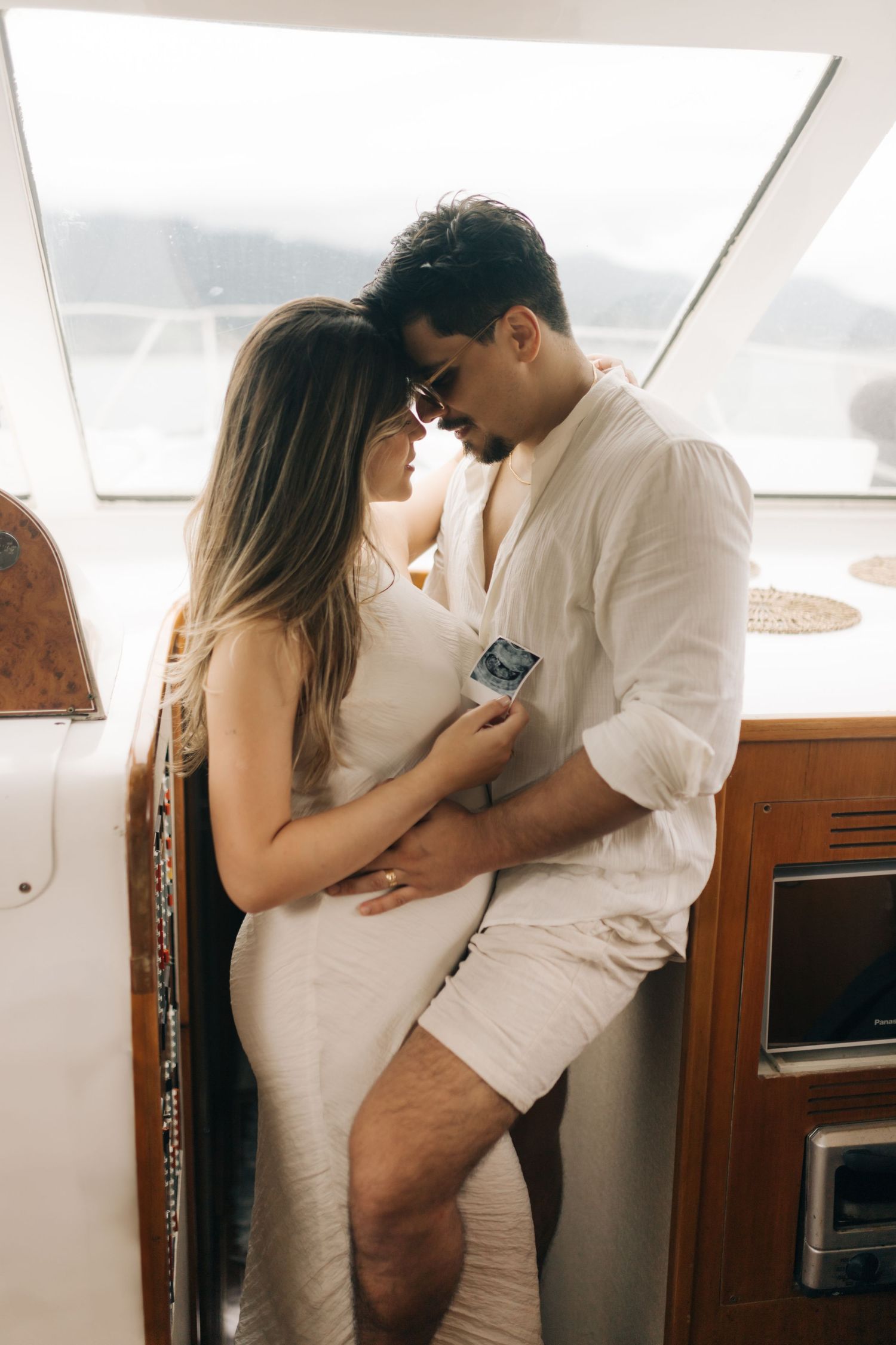 Intimate couple sharing a romantic moment aboard a yacht in casual summer attire.