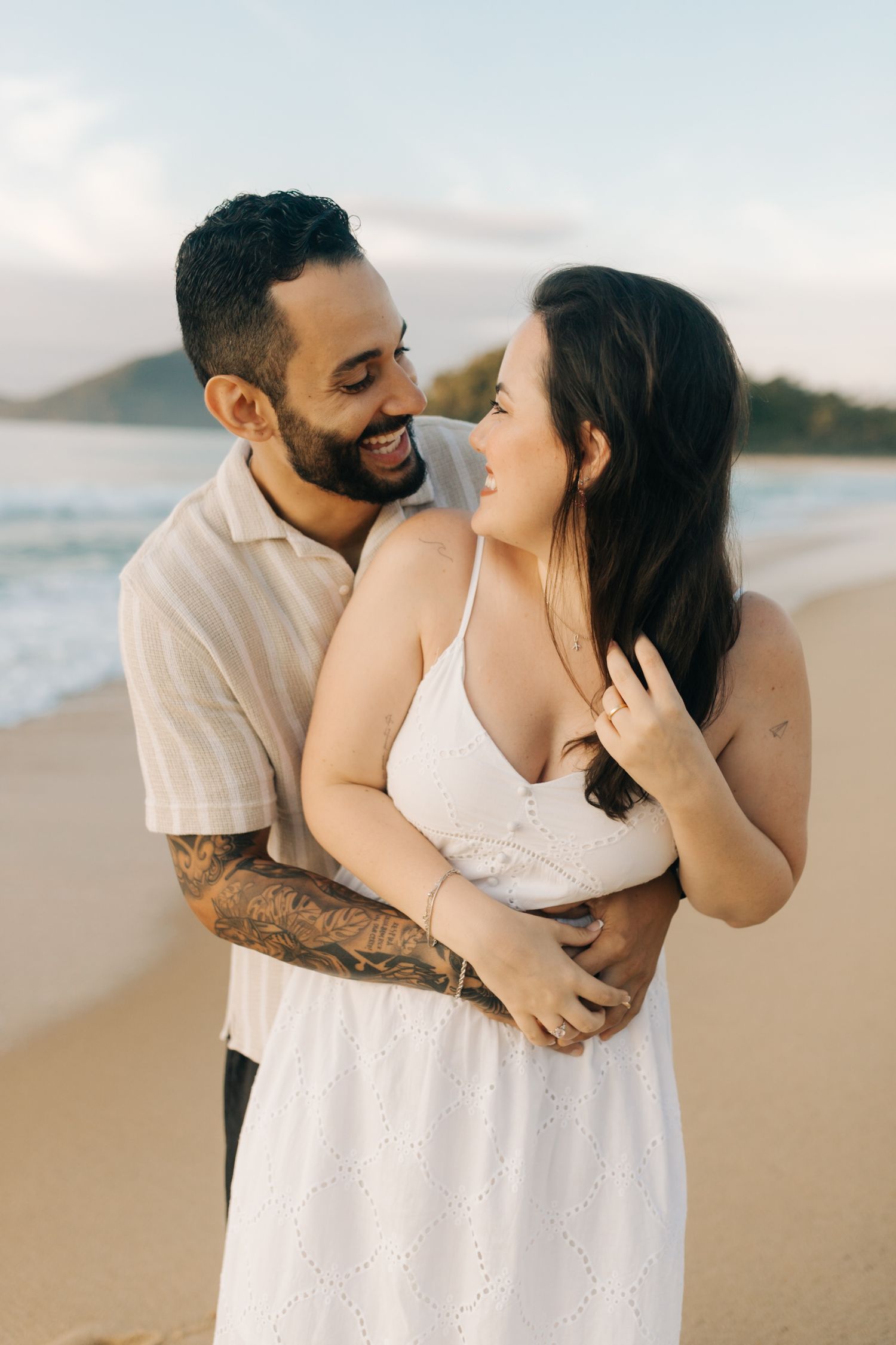 Candid shot of a couple embracing and laughing together on a scenic beach.