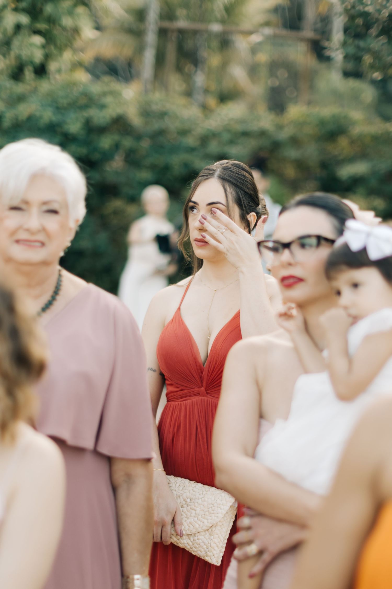Wedding party members wearing red and pink dresses gathered outdoors for a celebration.