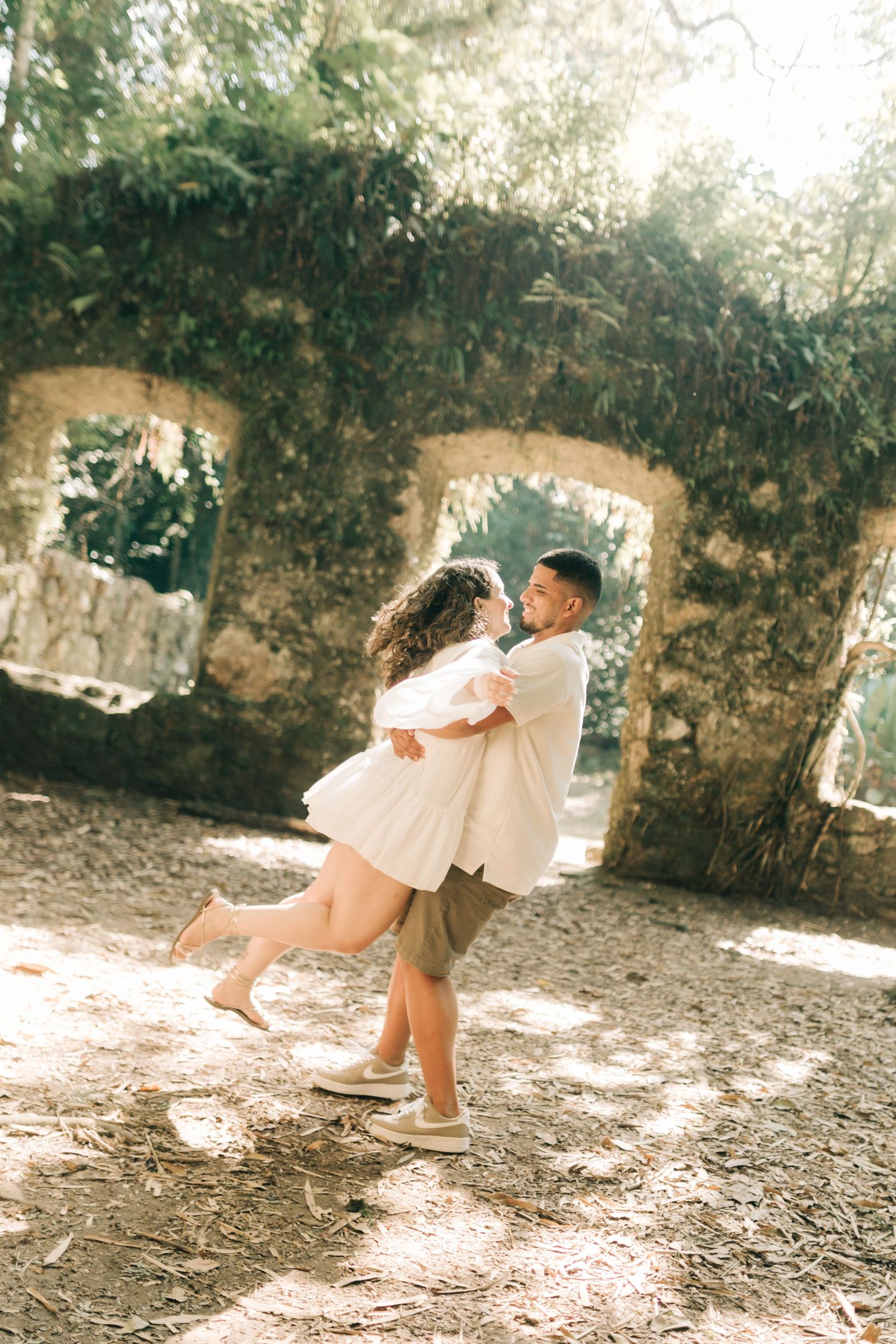 Playful couple twirling in ancient stone ruins filled with natural light.