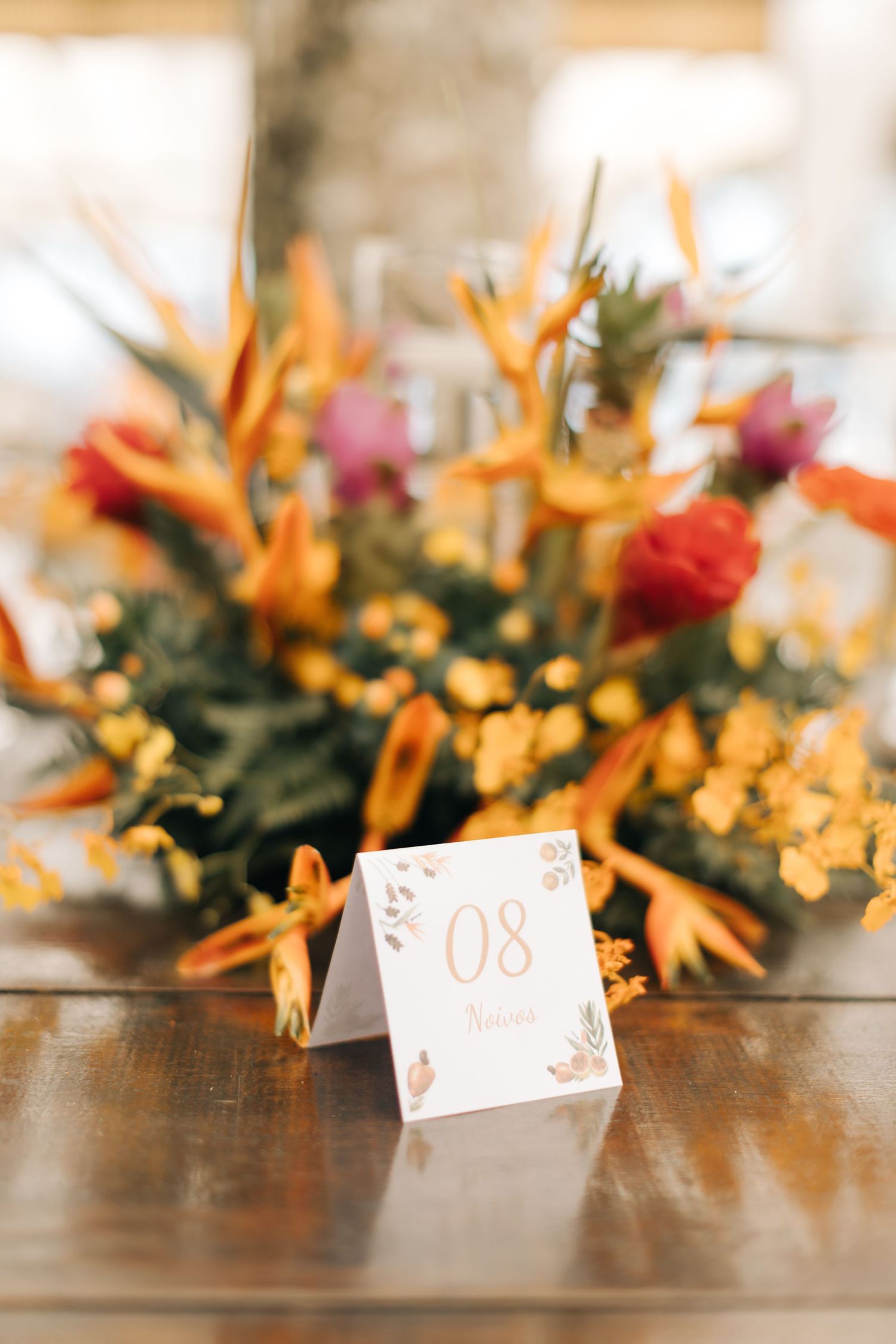 Tropical floral wedding centerpiece with orange birds of paradise and a table number card displaying number 08.