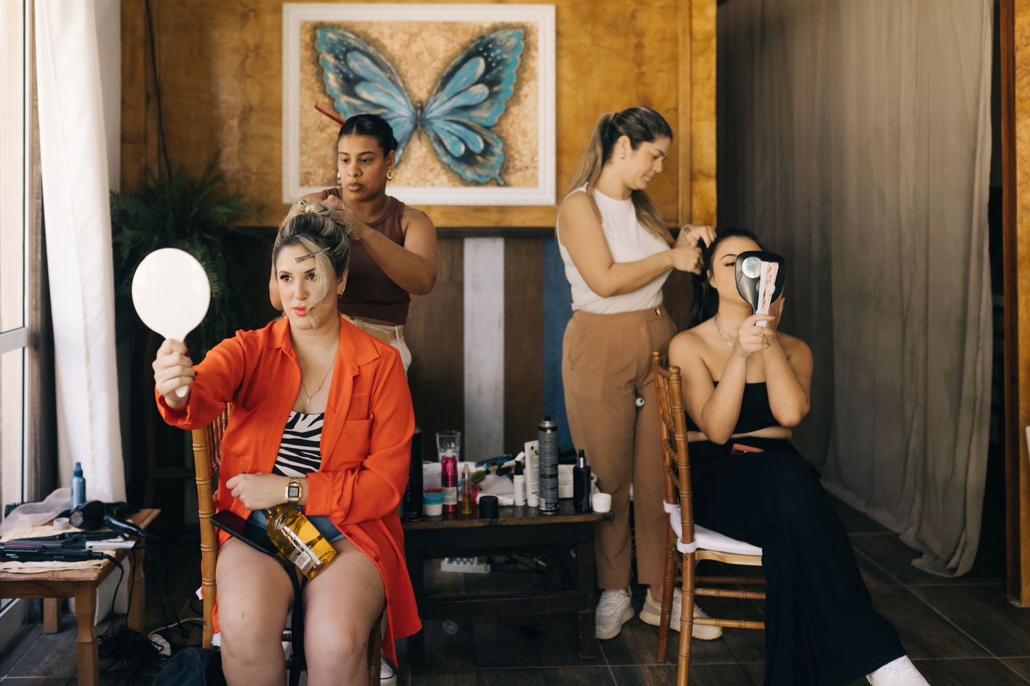 Behind the scenes preparation with stylists working in a room decorated with butterfly art.
