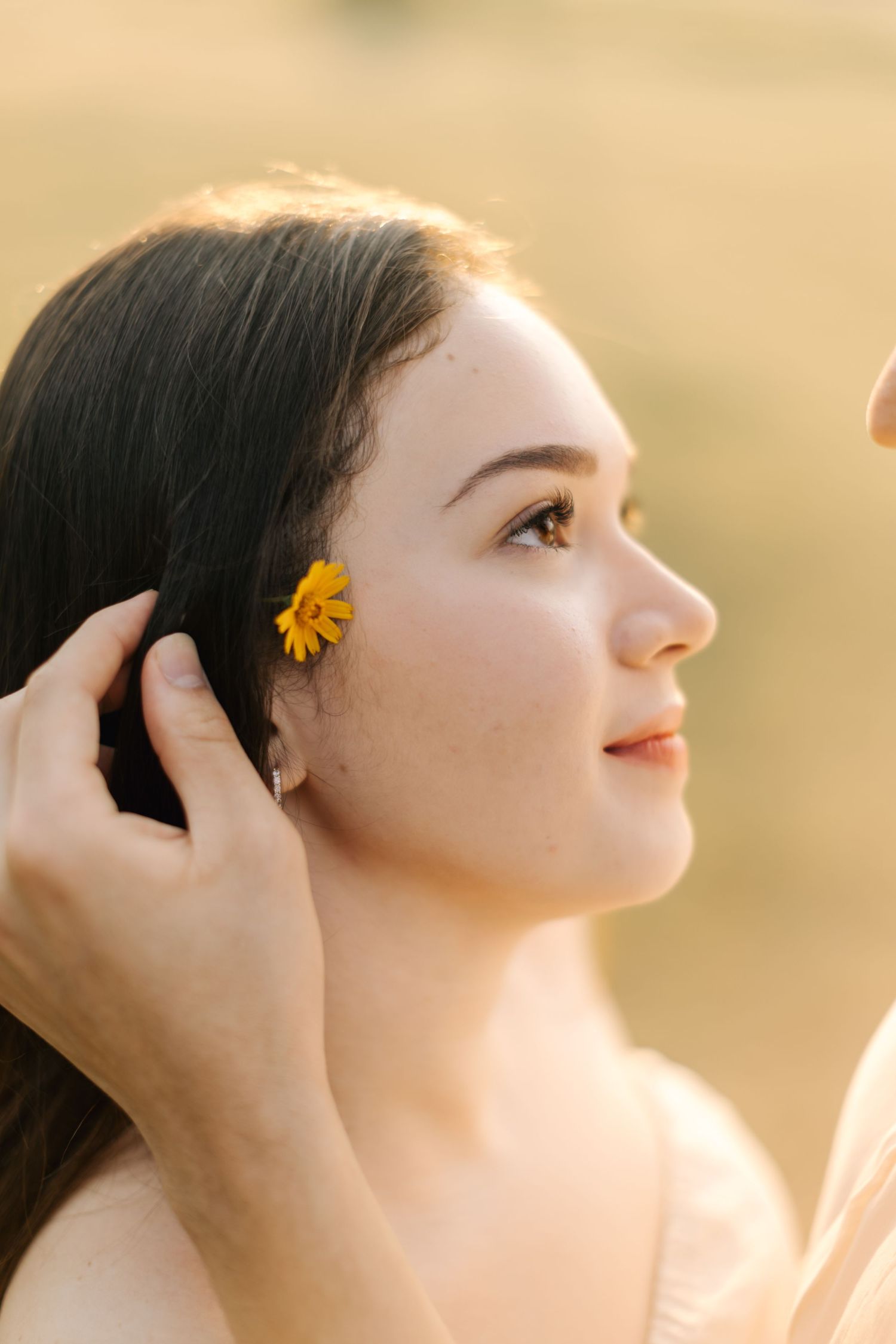 Profile view of person with yellow flower hair accessory during sunset portrait session.