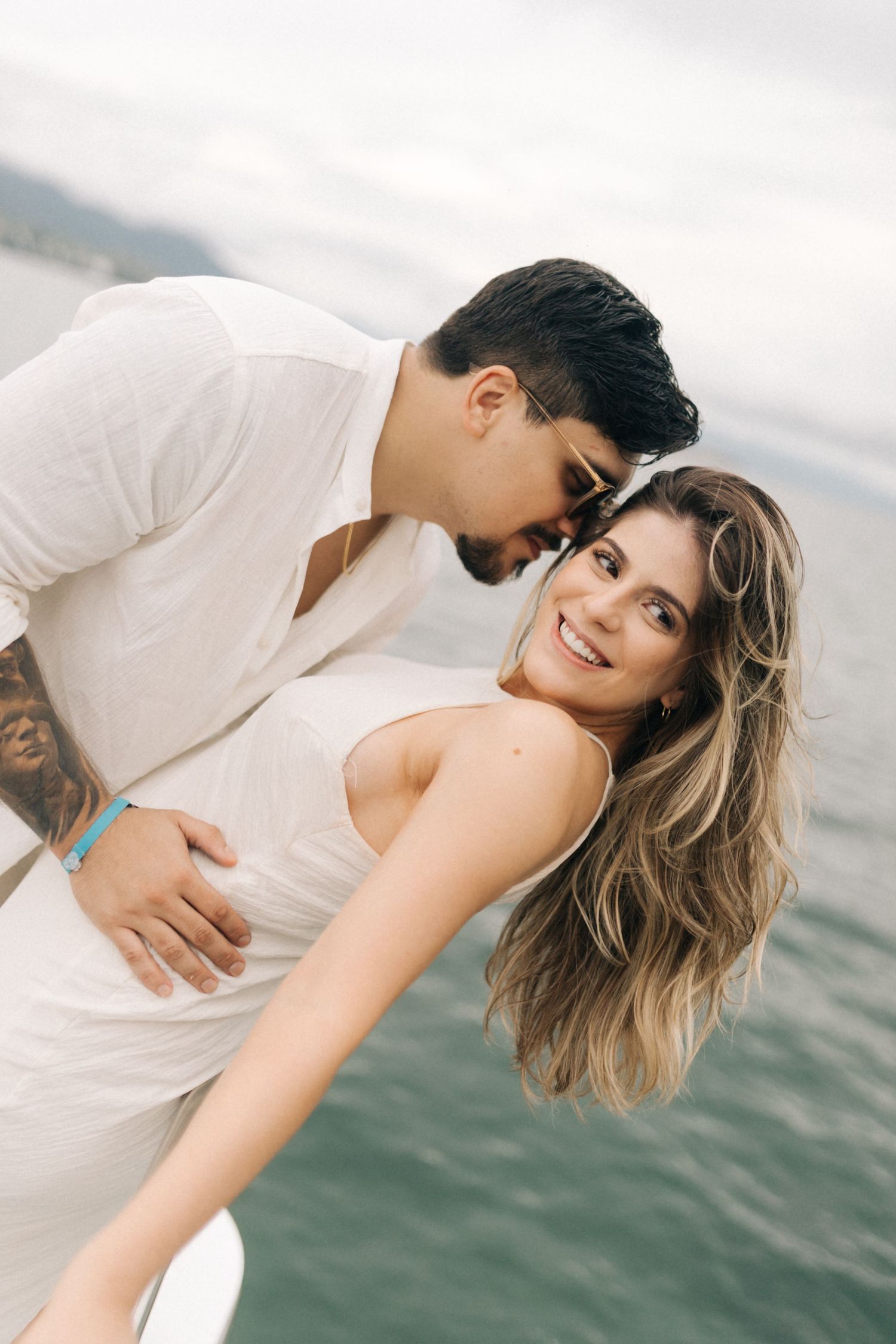 Two people share a tender moment while standing on a boat deck against a misty seascape.