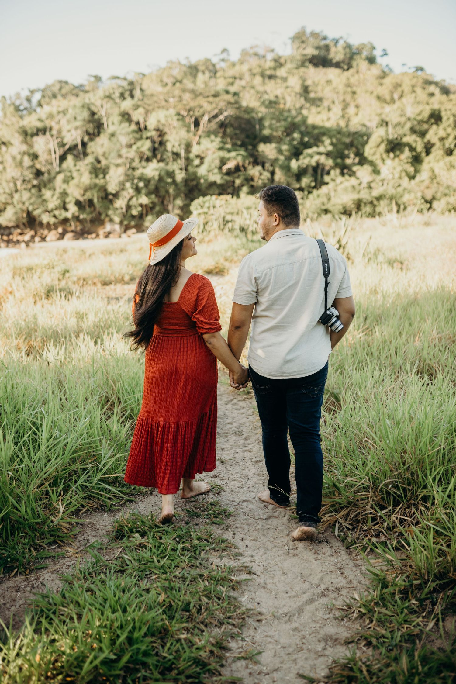 Couple strolling together on dirt path through scenic grassland landscape.