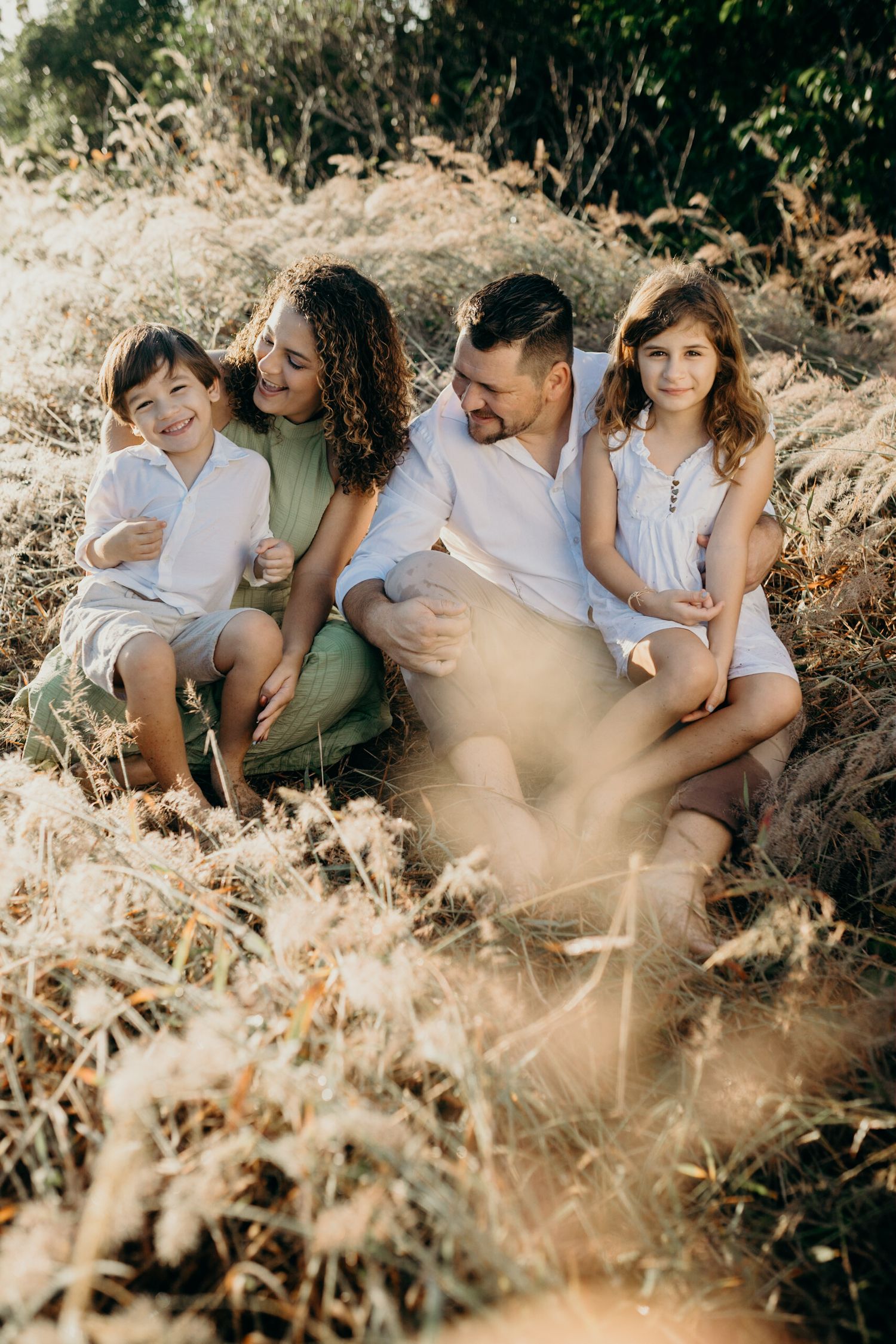 Intimate family photo session captured in tall grass with mountains in the background.
