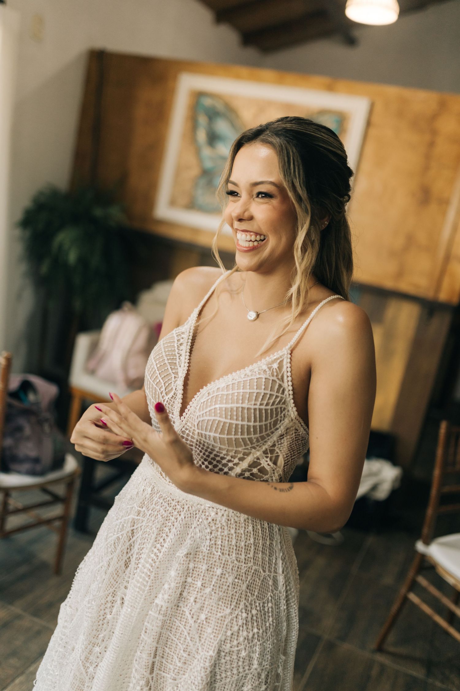 White lace wedding dress detail shown in a candid moment against wooden interior.