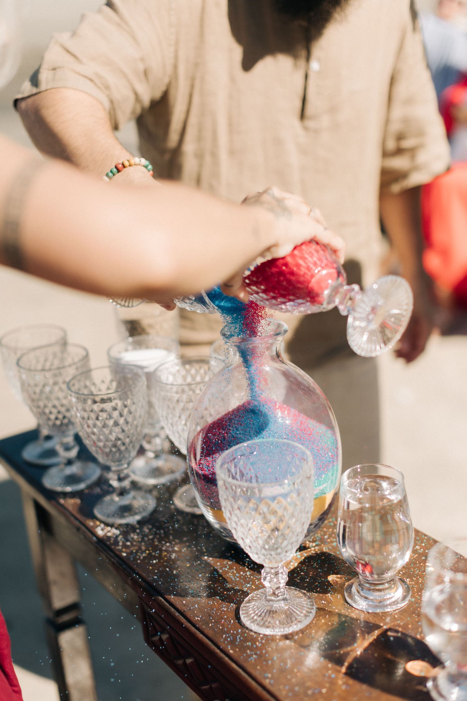Colorful cocktails being poured into vintage crystal glasses at outdoor event.