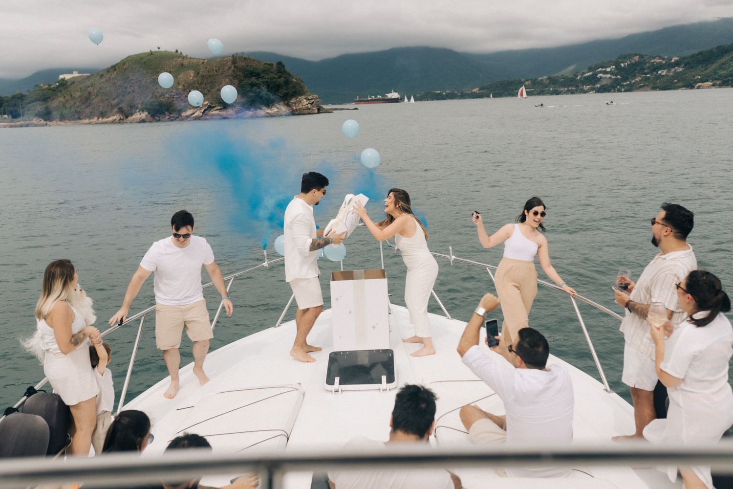 Celebration on a white yacht with blue smoke and partygoers dressed in matching white outfits.