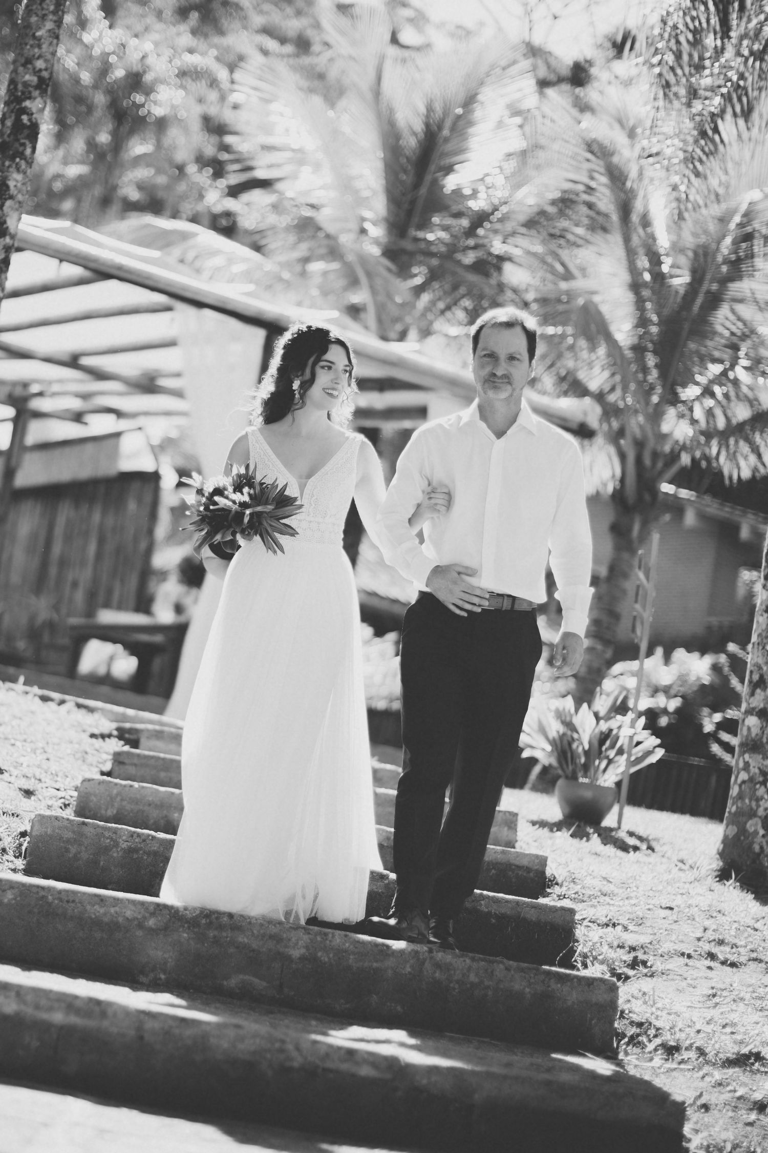 Black and white photo of a couple descending outdoor steps surrounded by palm trees.