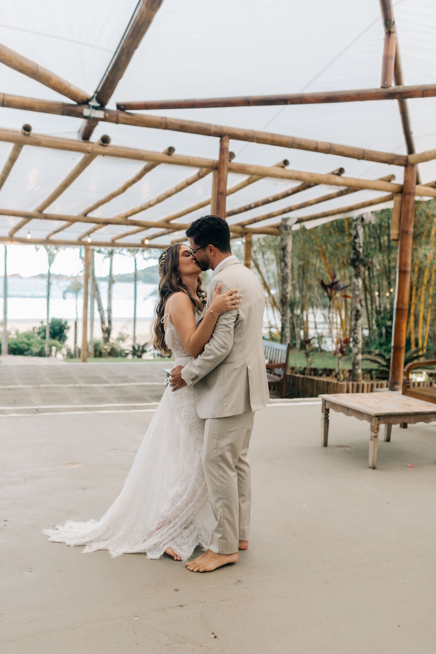 A romantic first dance moment under a wooden pergola by the beach.