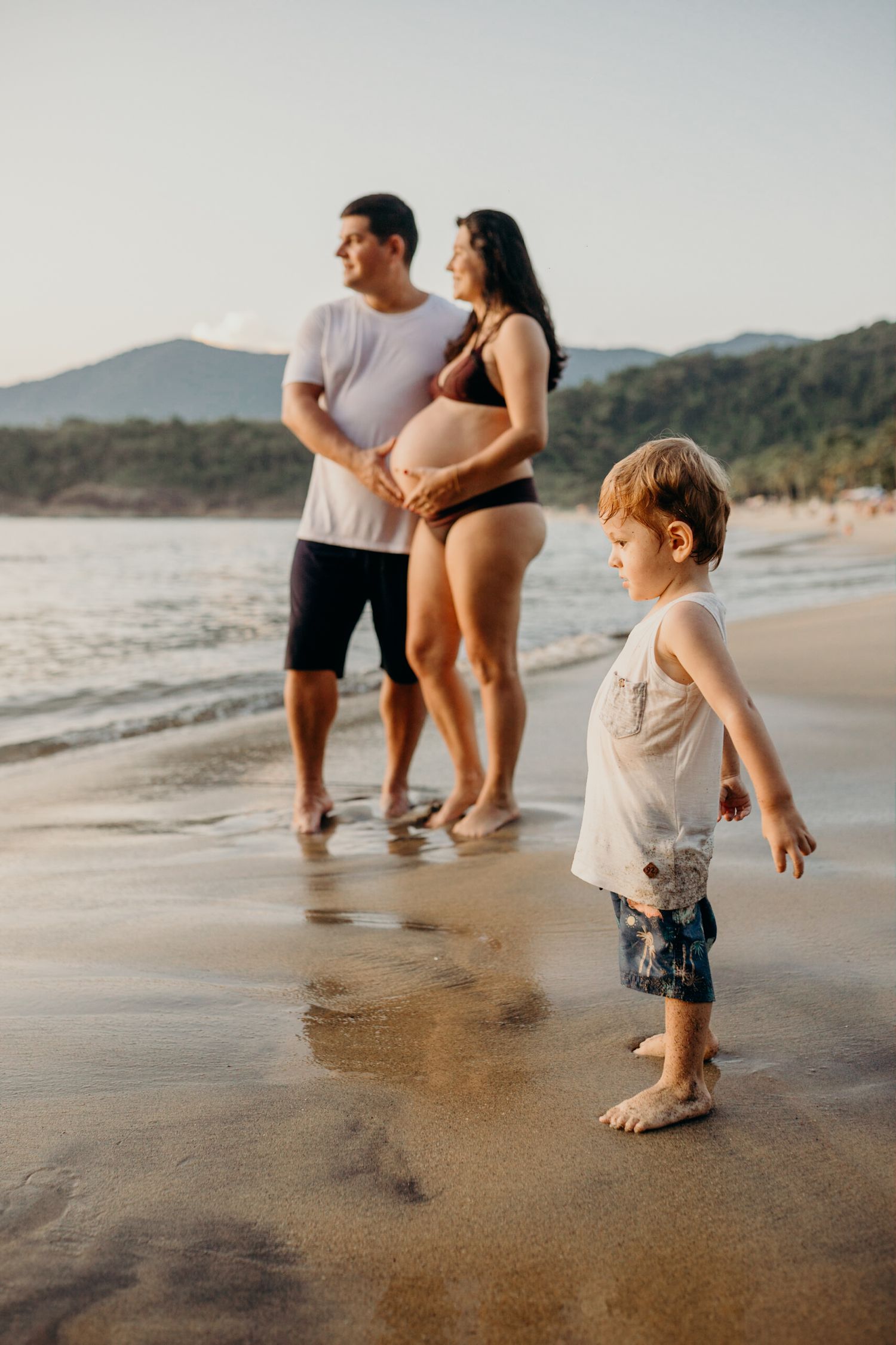 Family playing together in shallow ocean water during sunset.