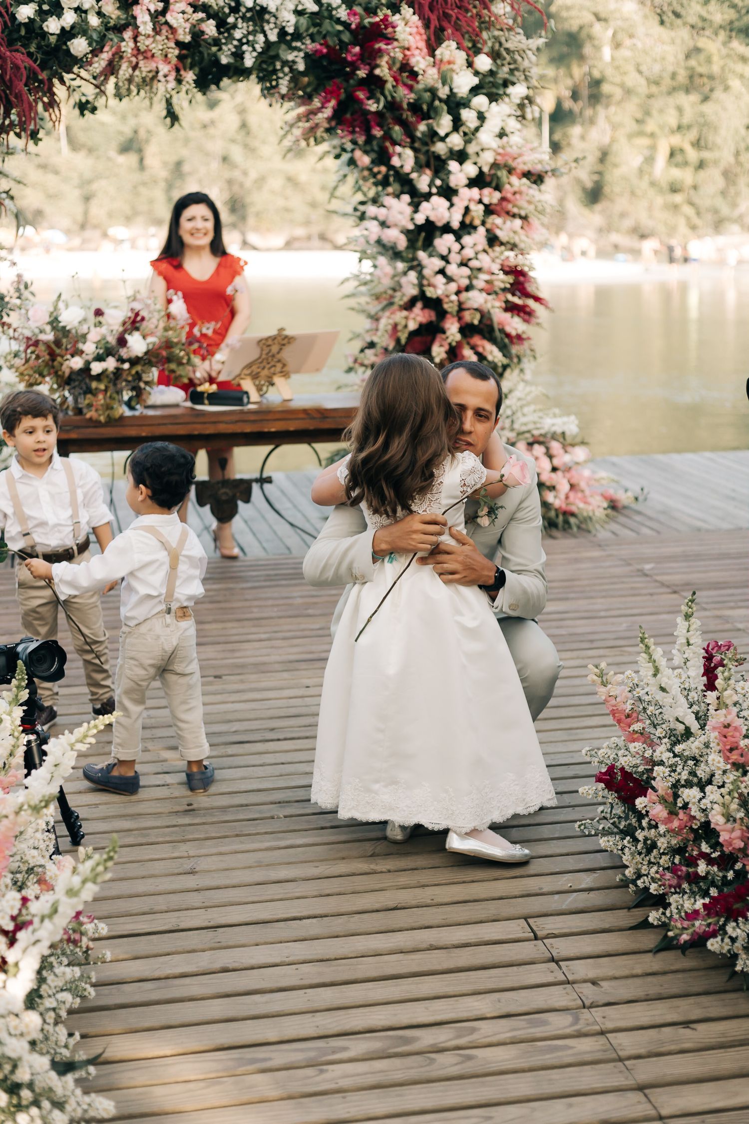 Dancing and celebration on flower-decorated wooden deck during outdoor wedding reception.