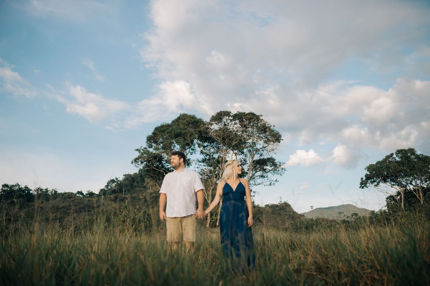 Scenic panorama of a couple walking through coastal grasslands under blue skies.