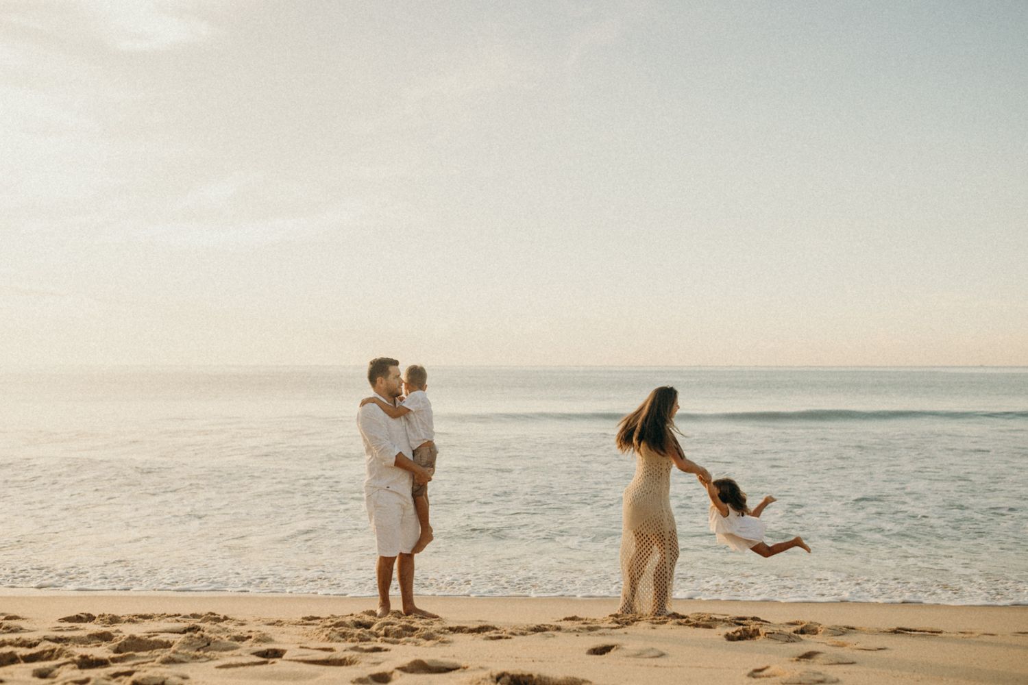 Family having fun and playing together on sandy beach at sunset.