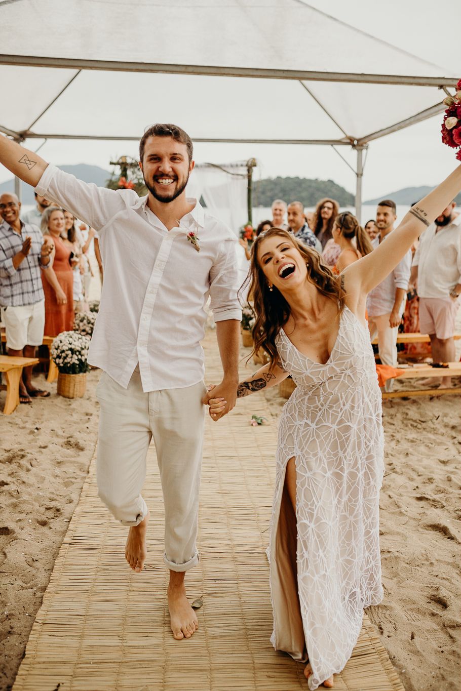 A jubilant couple celebrates during their barefoot beach wedding ceremony.