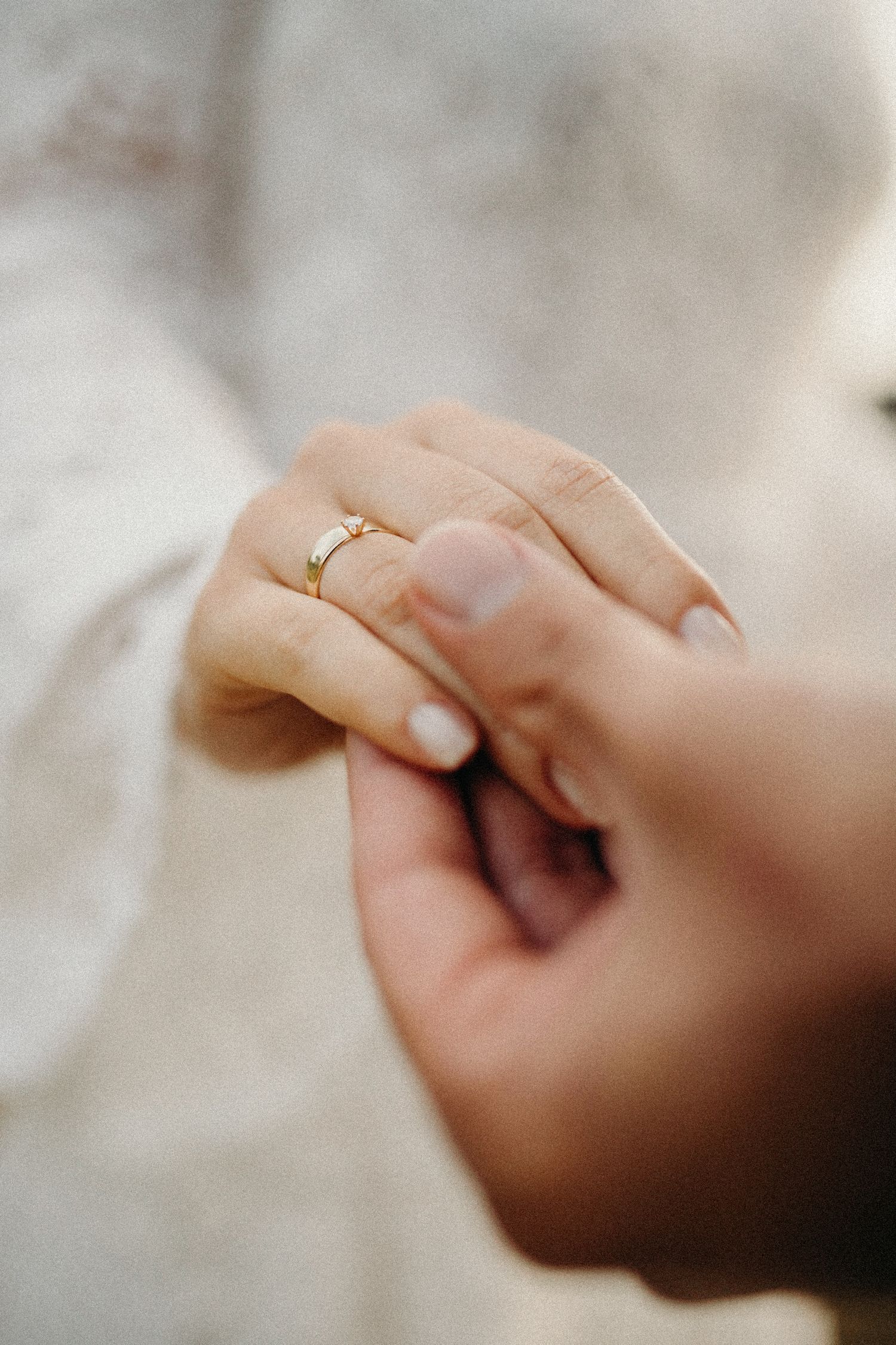Macro shot of engagement rings on hands with soft bokeh background.
