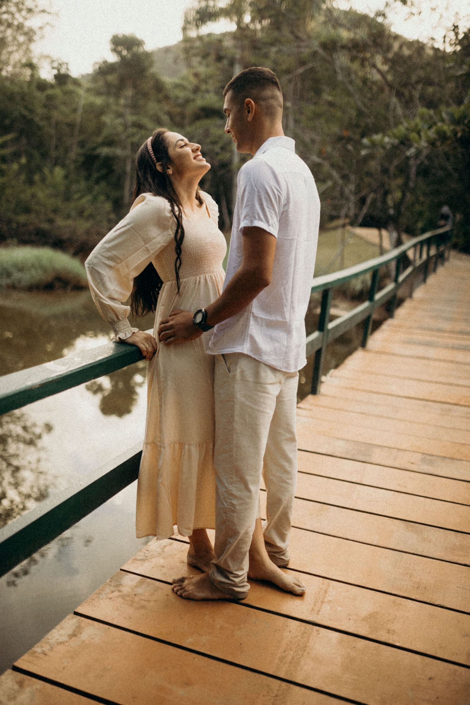 Couple sharing romantic moments on a wooden bridge over water.