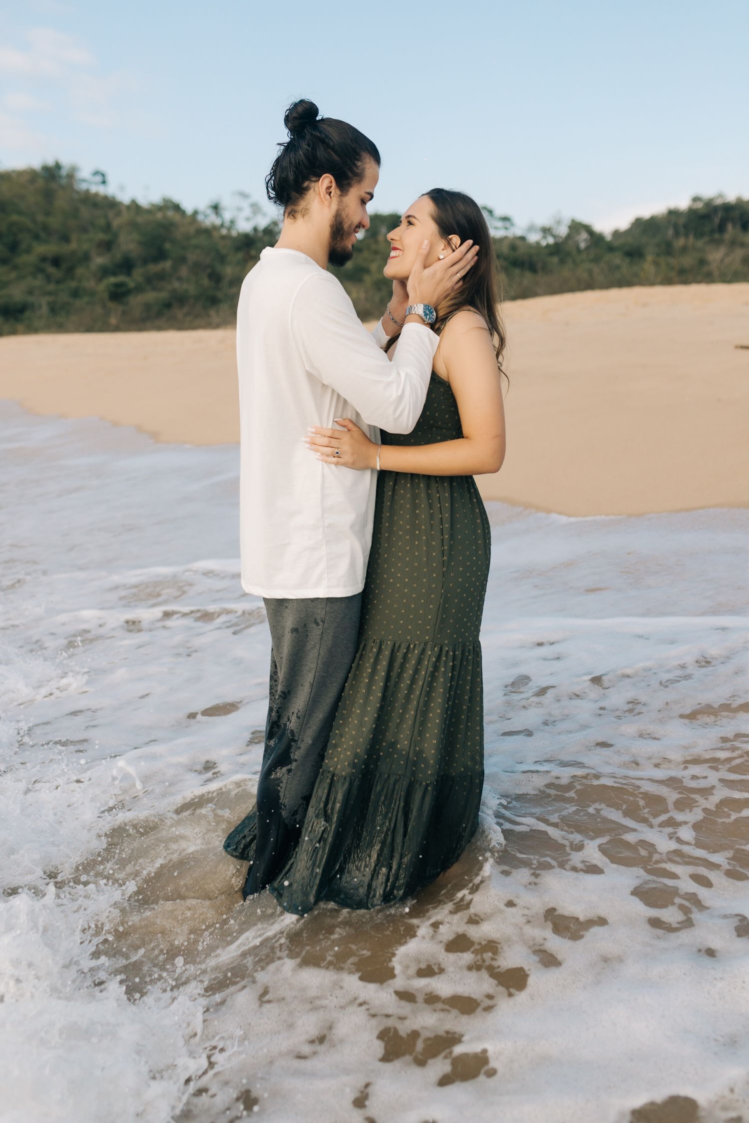 A romantic couple embraces in the shallow waters of a beautiful beach.