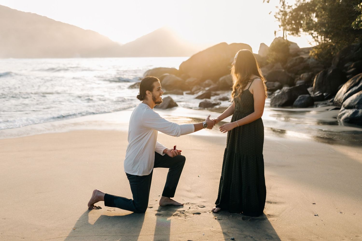 A heartfelt proposal taking place on a sandy beach during golden hour.