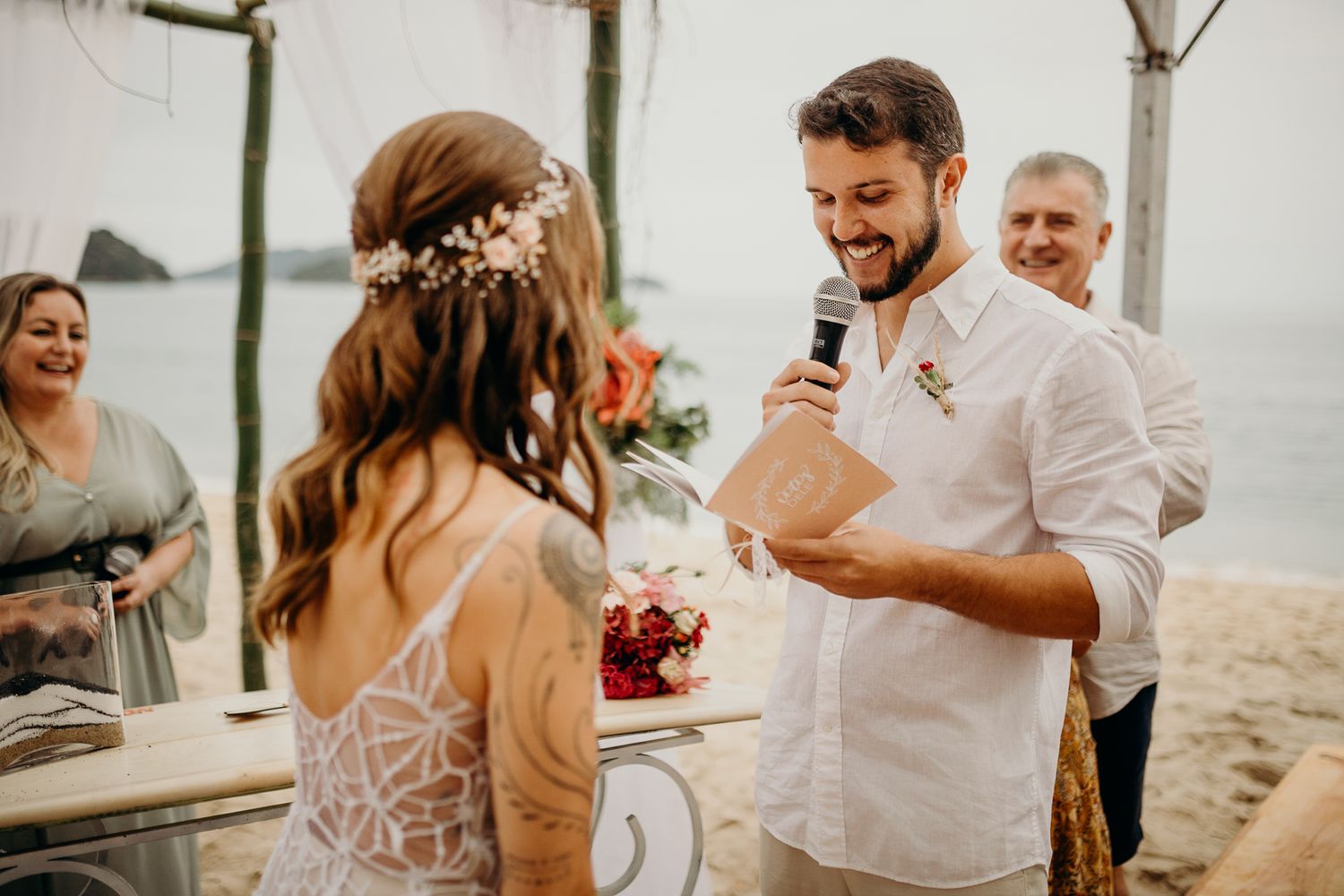 A beach wedding ceremony captures an emotional vow exchange under a tent by the ocean.