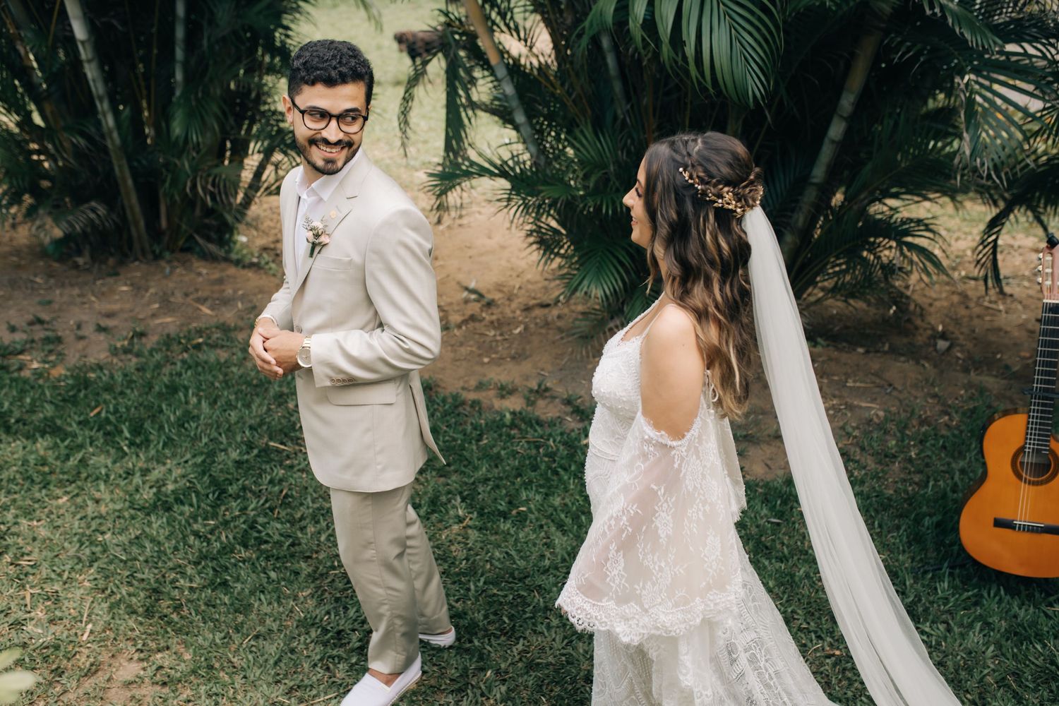 A joyful wedding moment captured in a tropical garden setting with an acoustic guitar prop.
