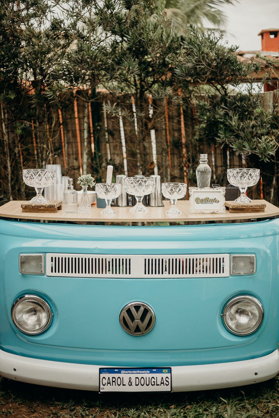 Vintage turquoise VW bus converted into a drink station with crystal glasses on display.