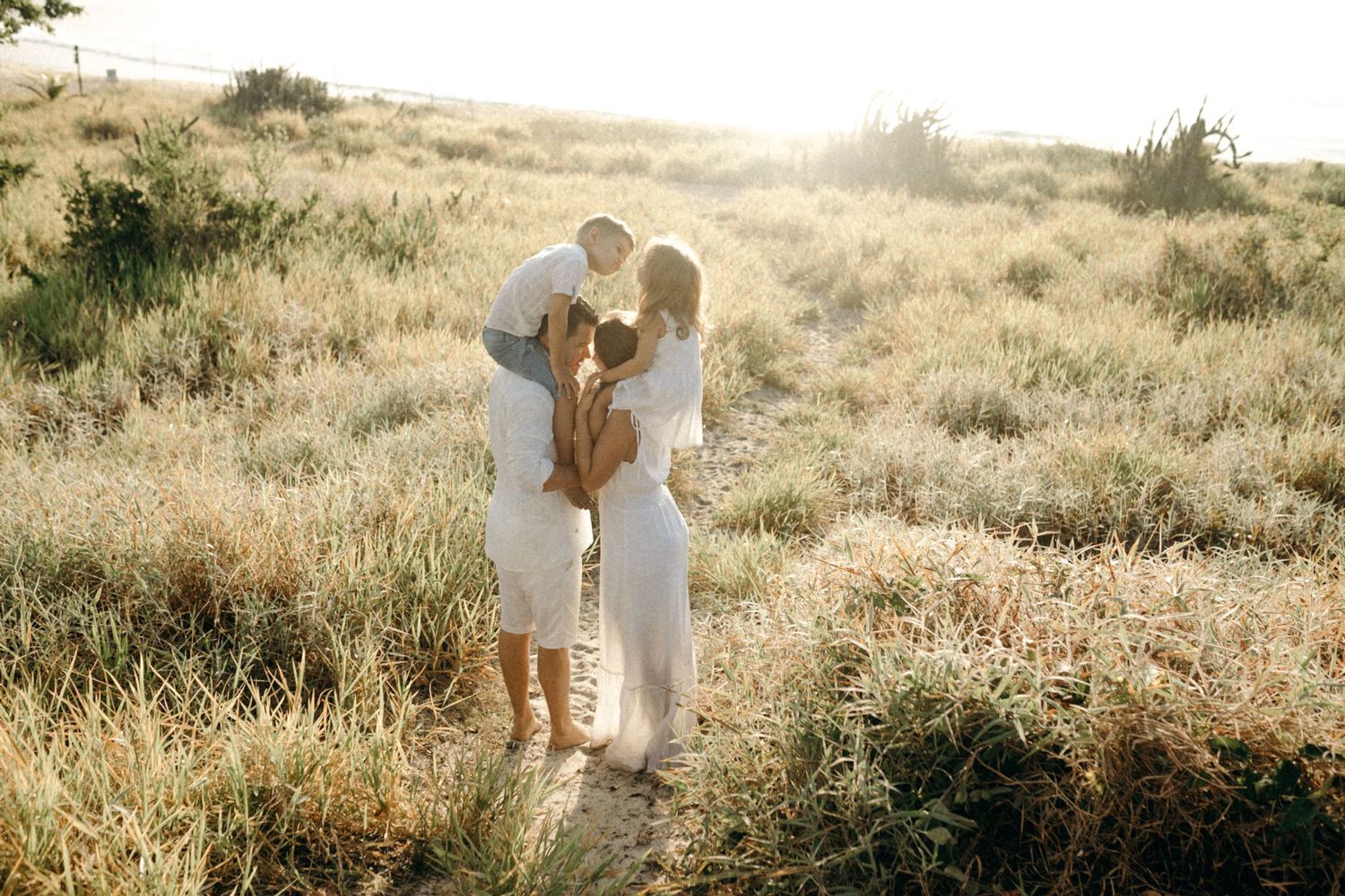 Family portrait session in a sun-drenched field with golden light.