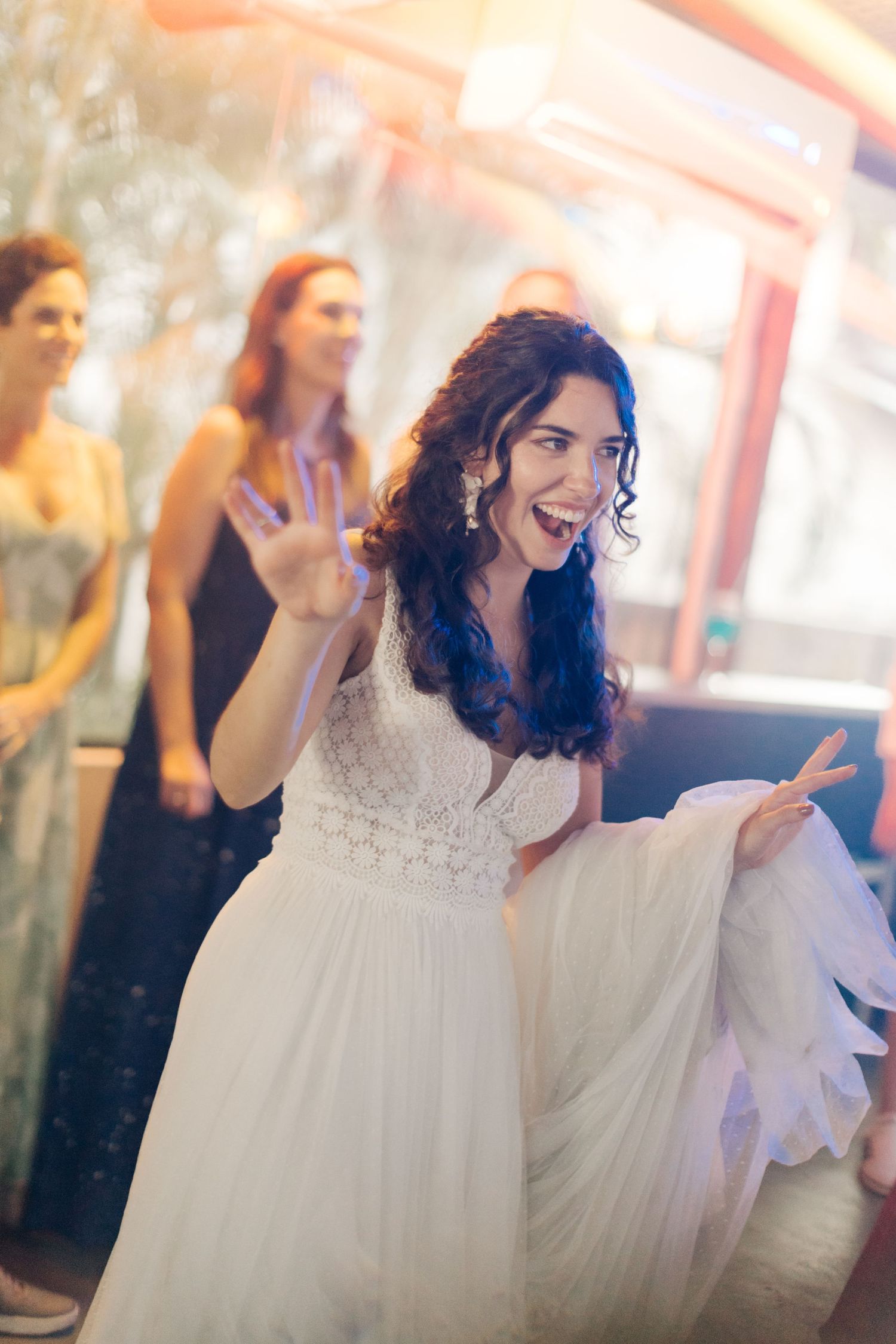 Person in white lace dress dancing joyfully at a celebration.