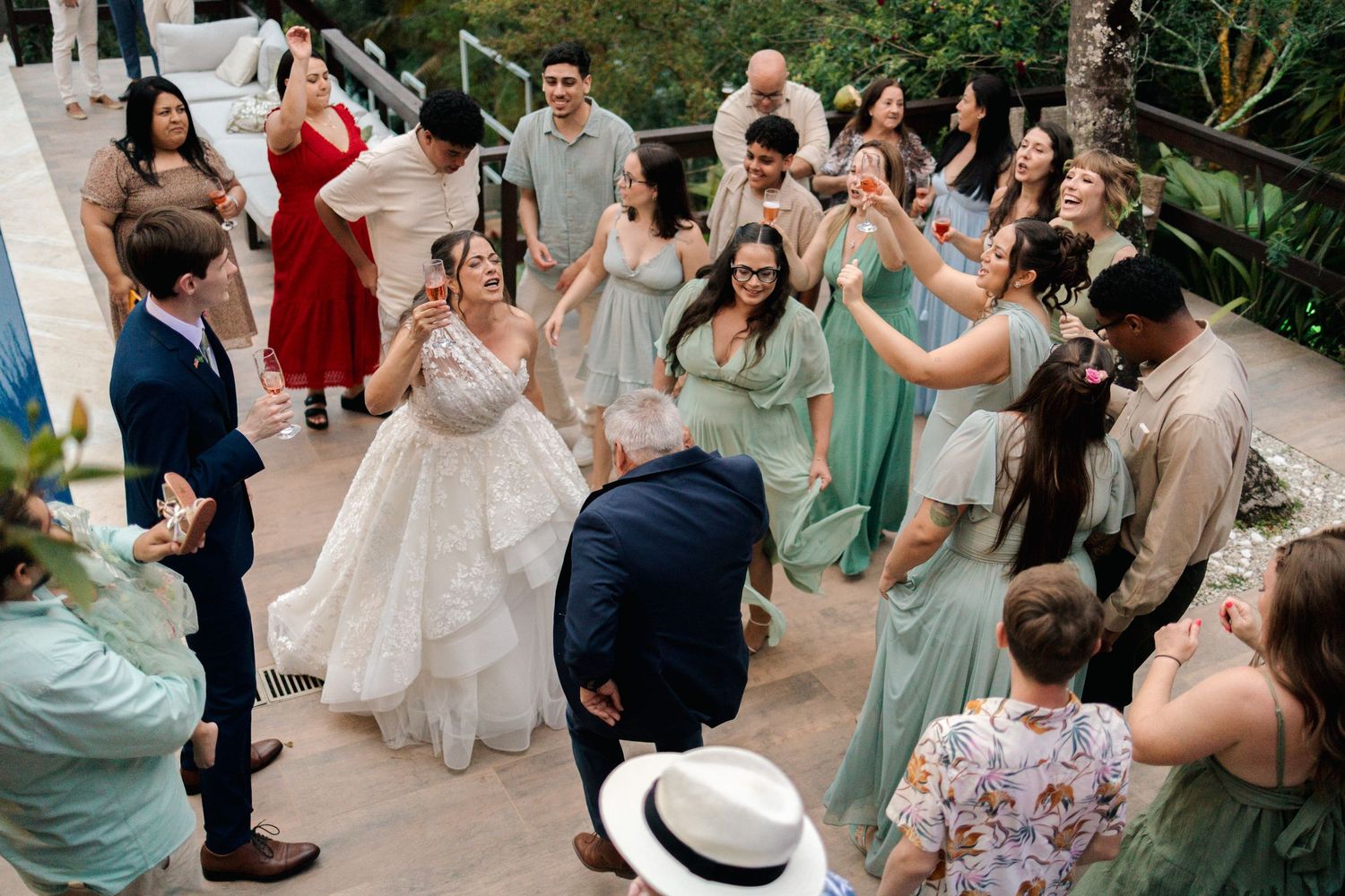 Large group of wedding guests dancing and celebrating at an outdoor garden party reception.