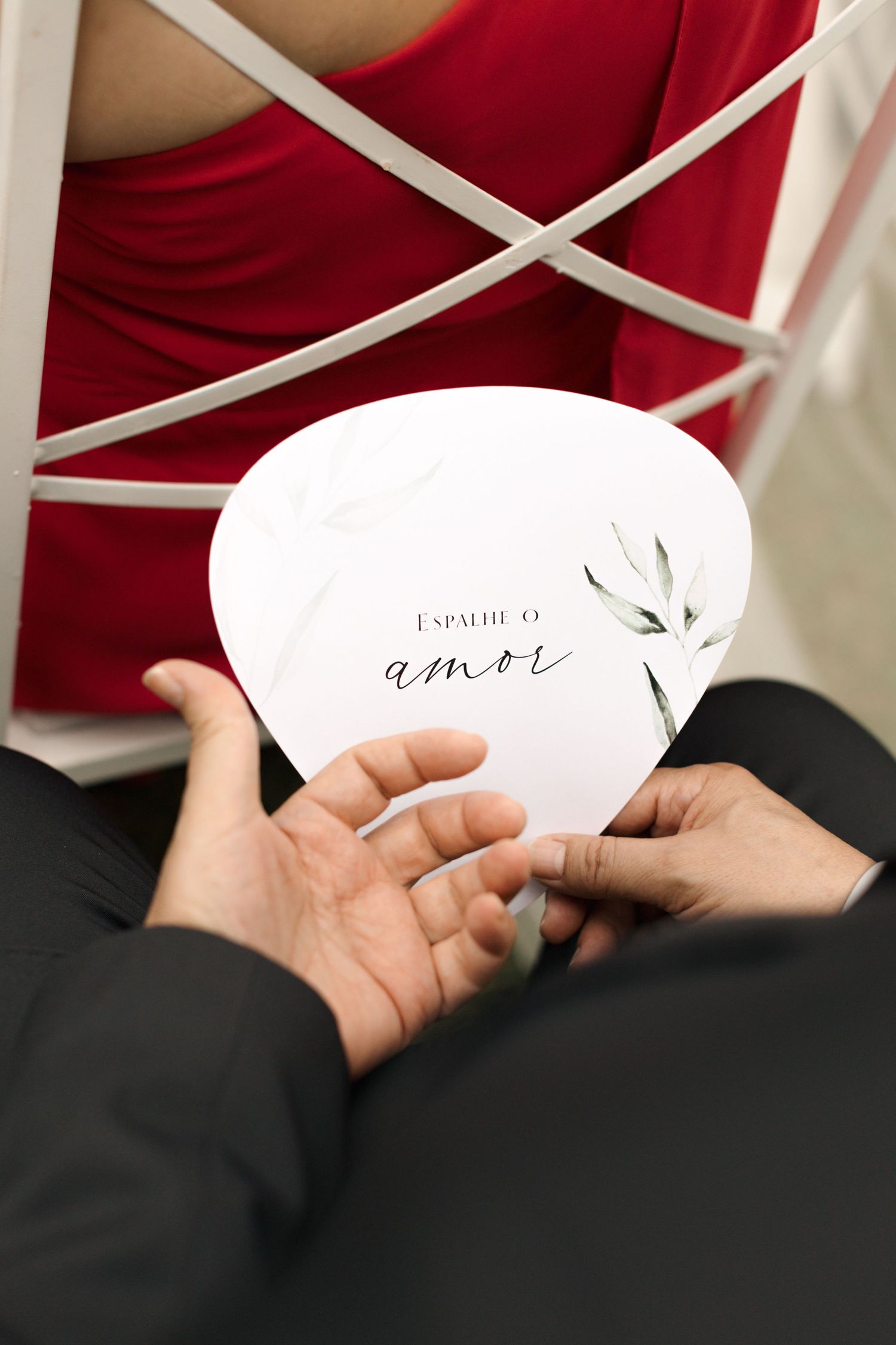 Hands holding white wedding program card with 'amor' text design.