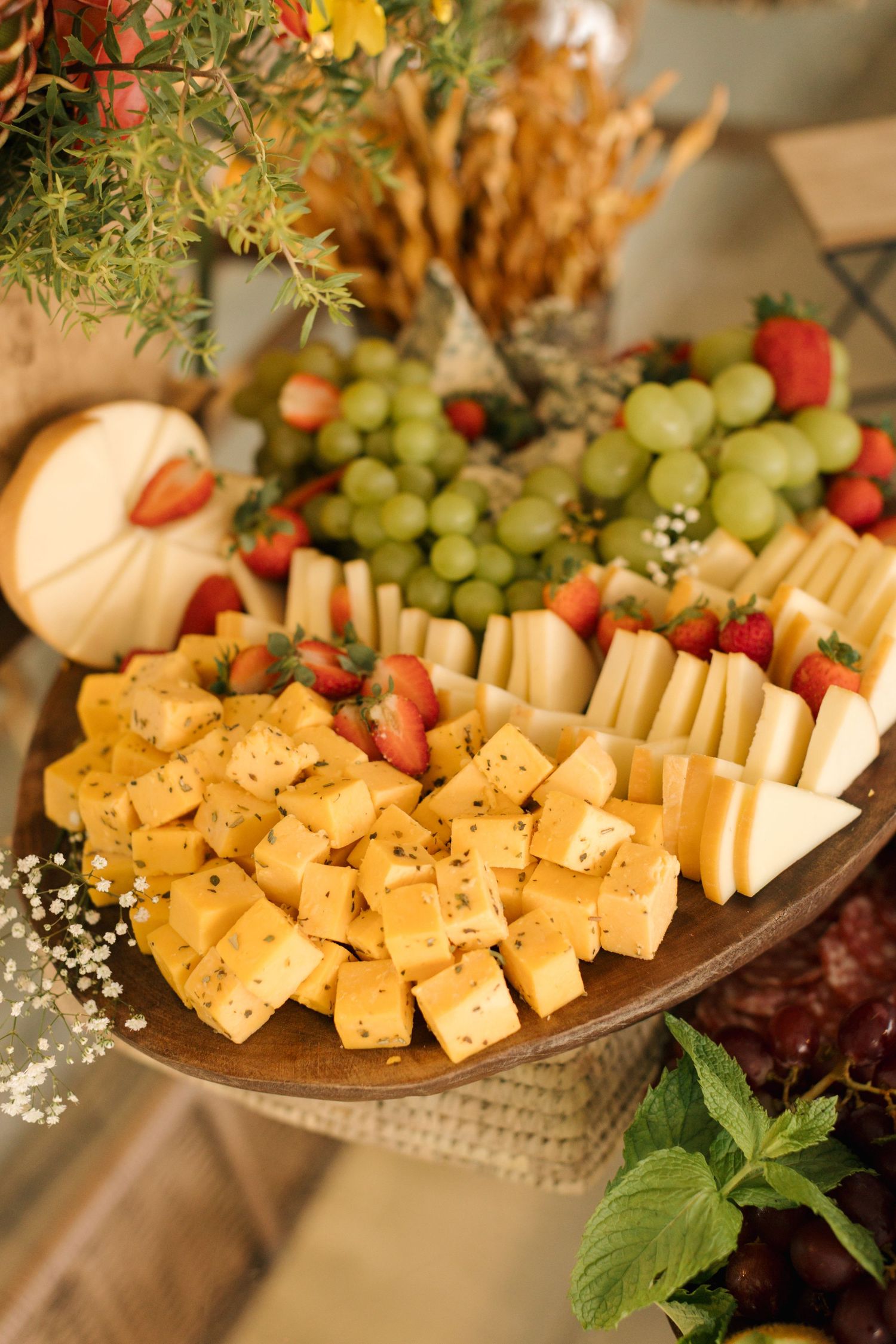 A beautifully arranged cheese and fruit platter with grapes and crackers at a wedding reception.