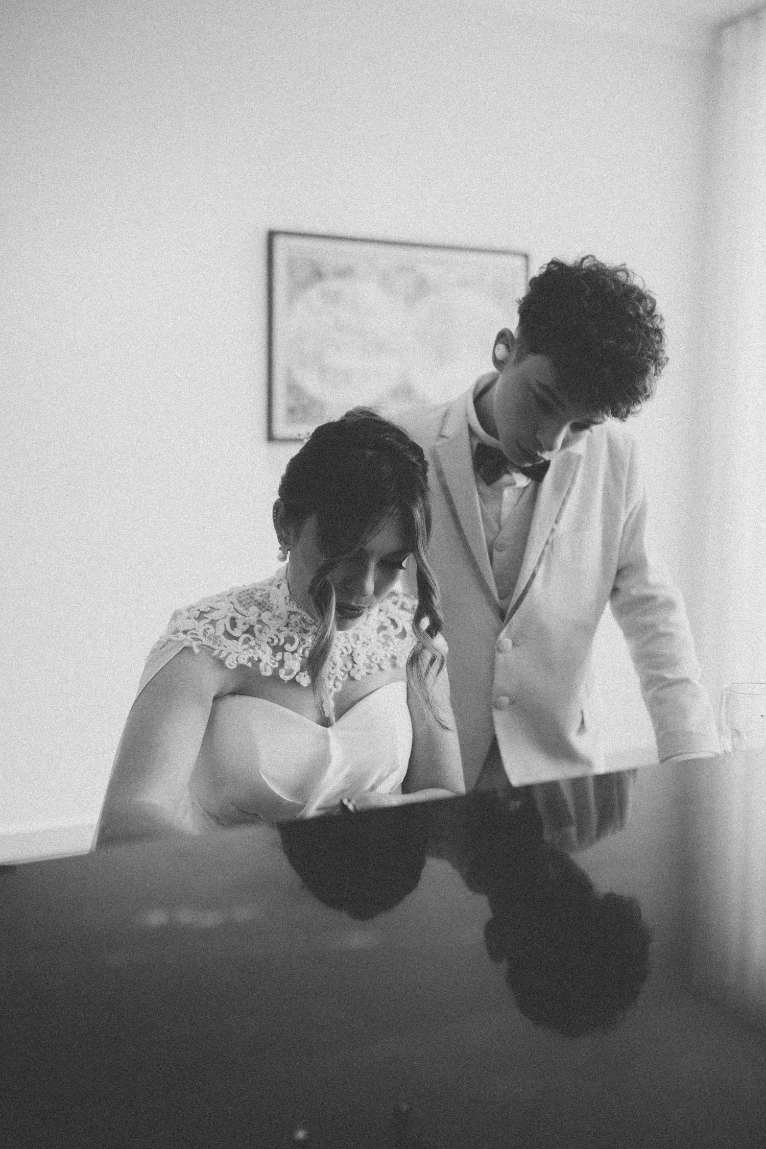 A romantic black and white moment captured between two people in formal wedding attire.