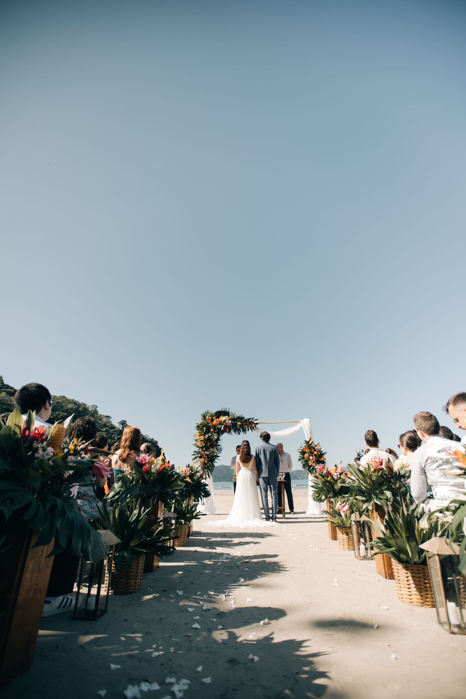 Floral-lined aisle at beach wedding ceremony with ocean views.