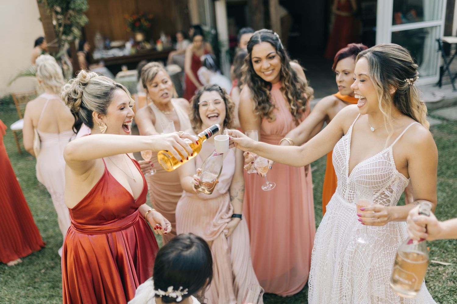 Wedding party in pink and red dresses celebrating outdoors.