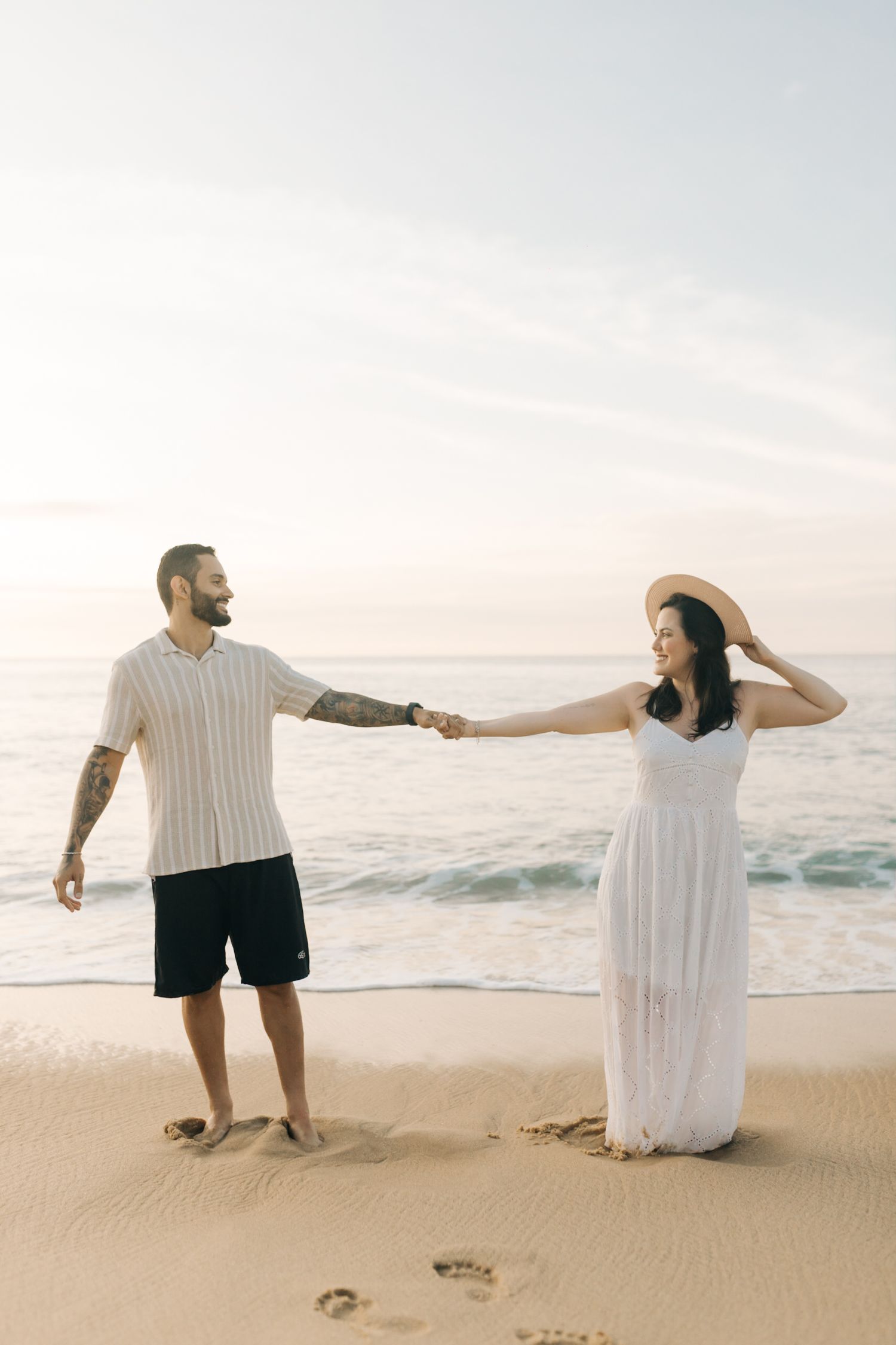 Couple dancing together on the beach with waves crashing in the background.
