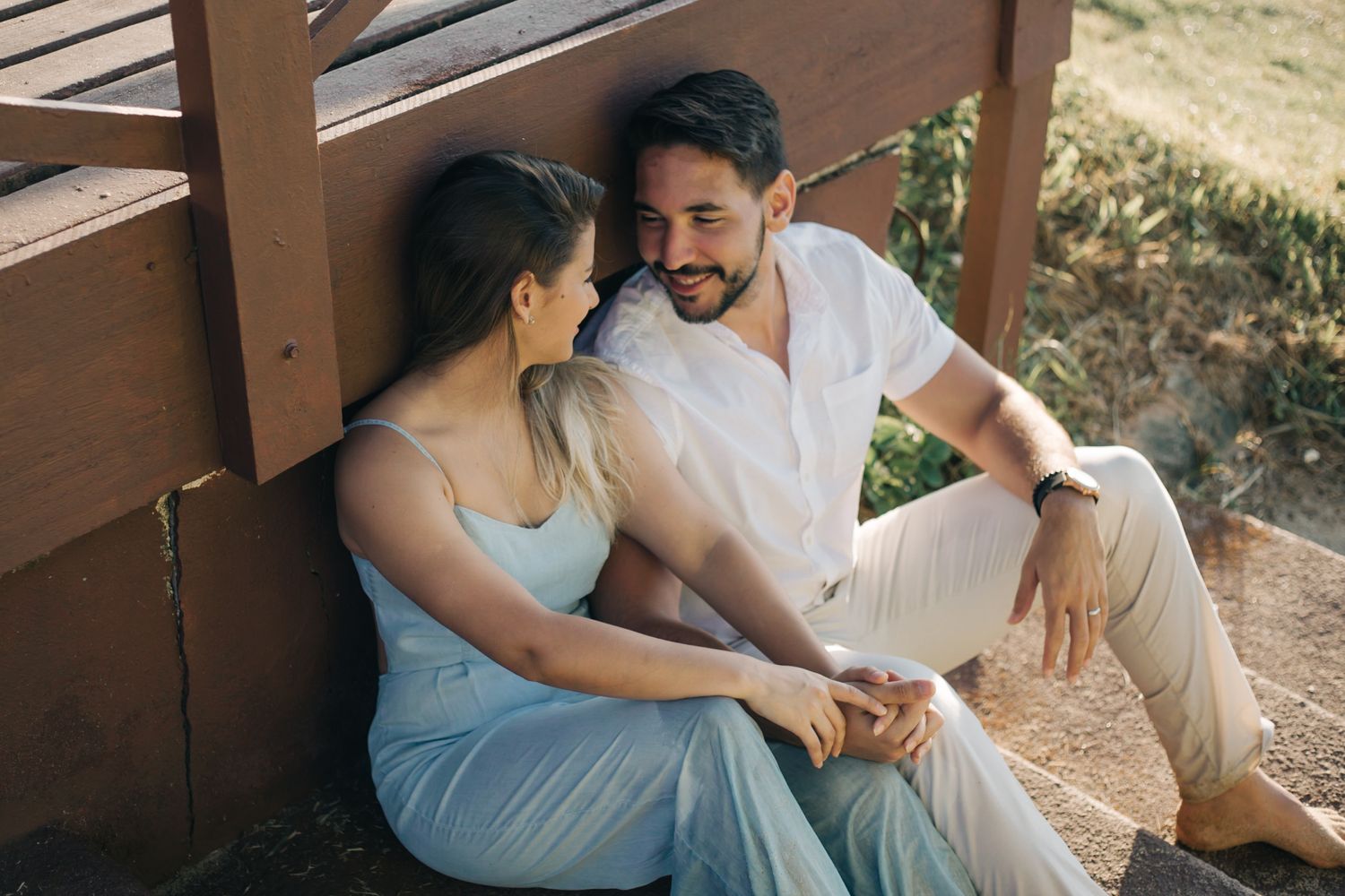 Casual outdoor couple photoshoot on wooden deck in natural lighting.
