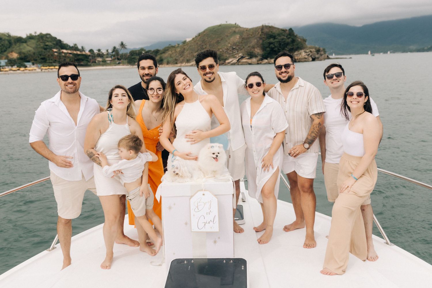 Friends and family gather on a boat deck for a gender reveal celebration.